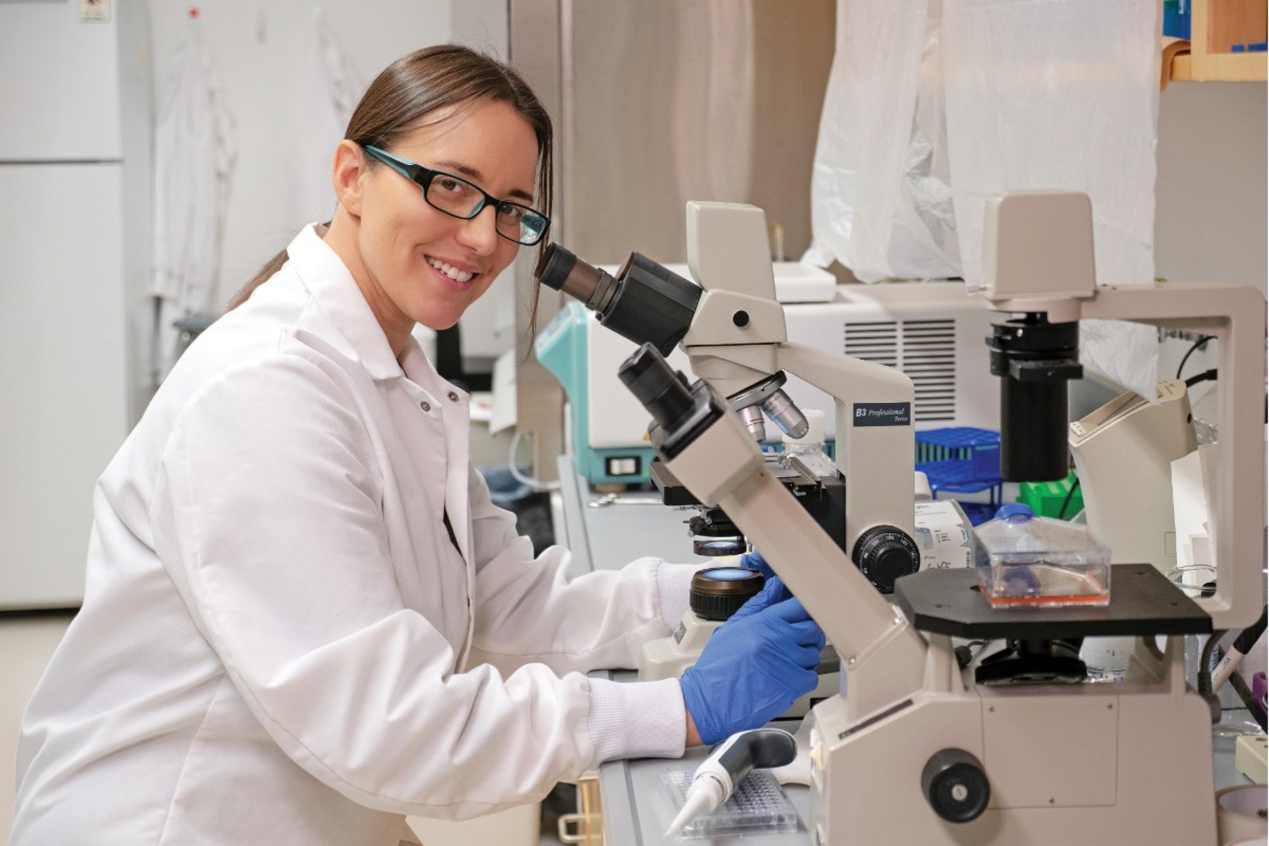 A scientist in a lab in front of a microscope.