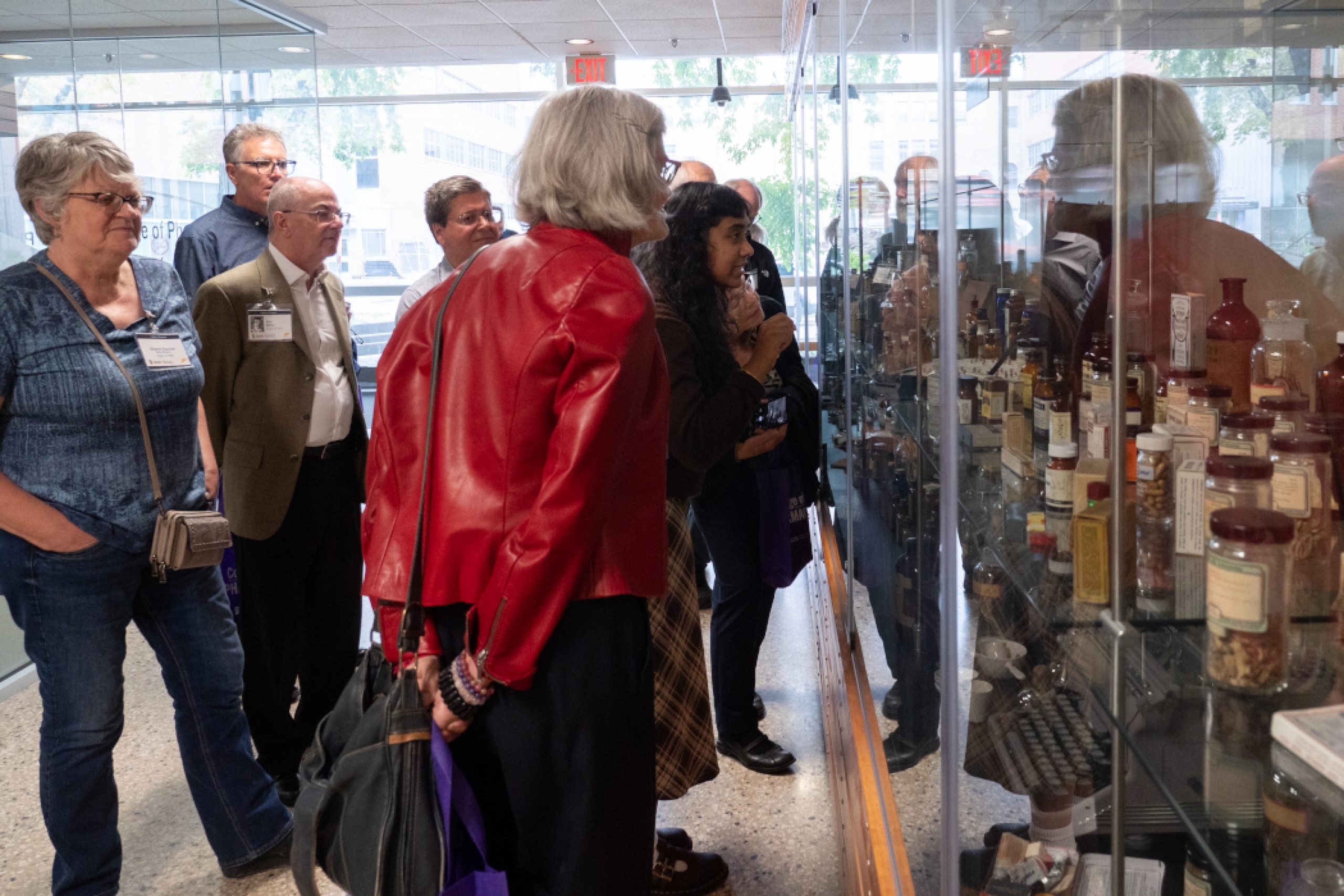 Pharmacy alumni look at a historical display behind glass. 