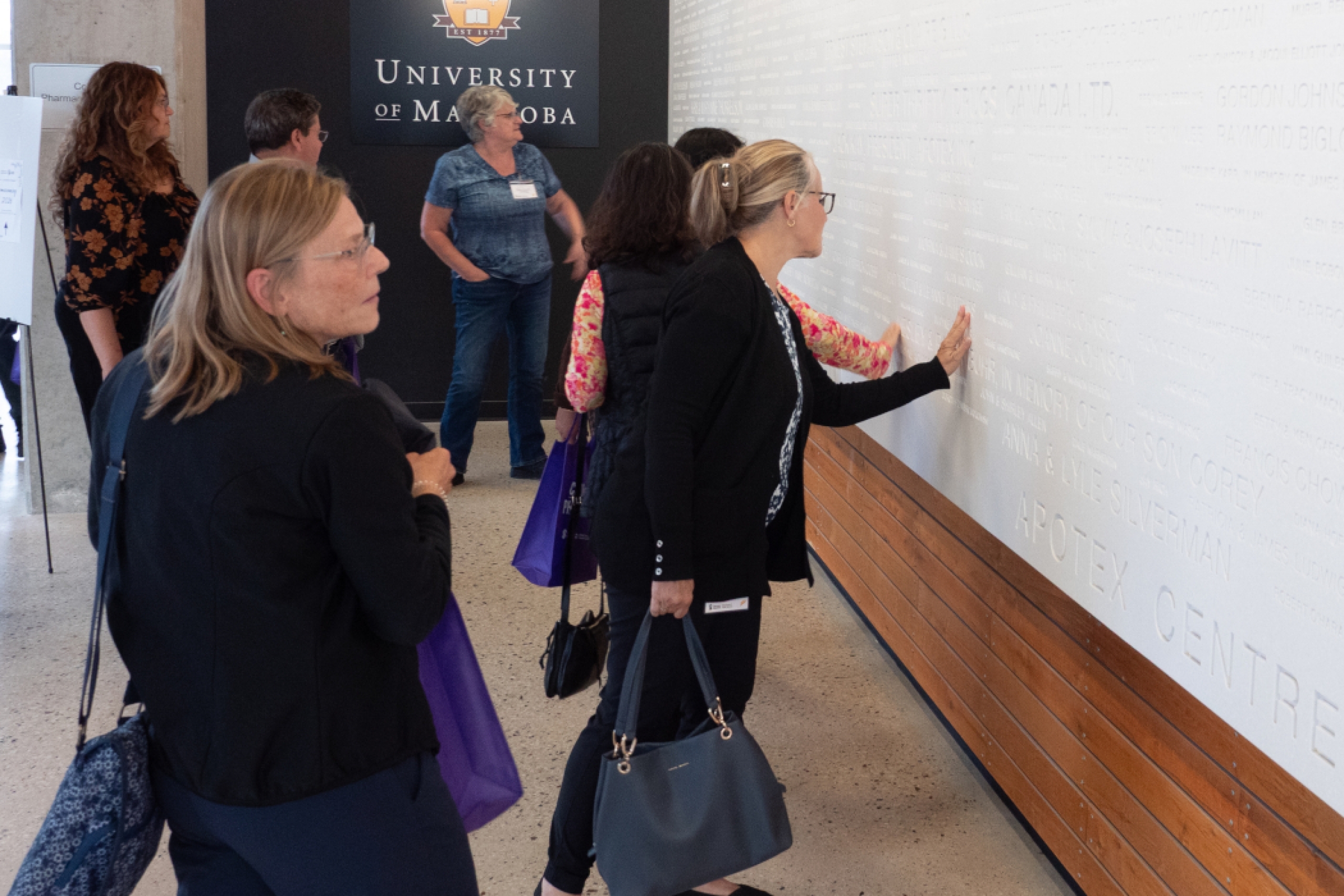 Pharmacy alumni look at the donor wall. 