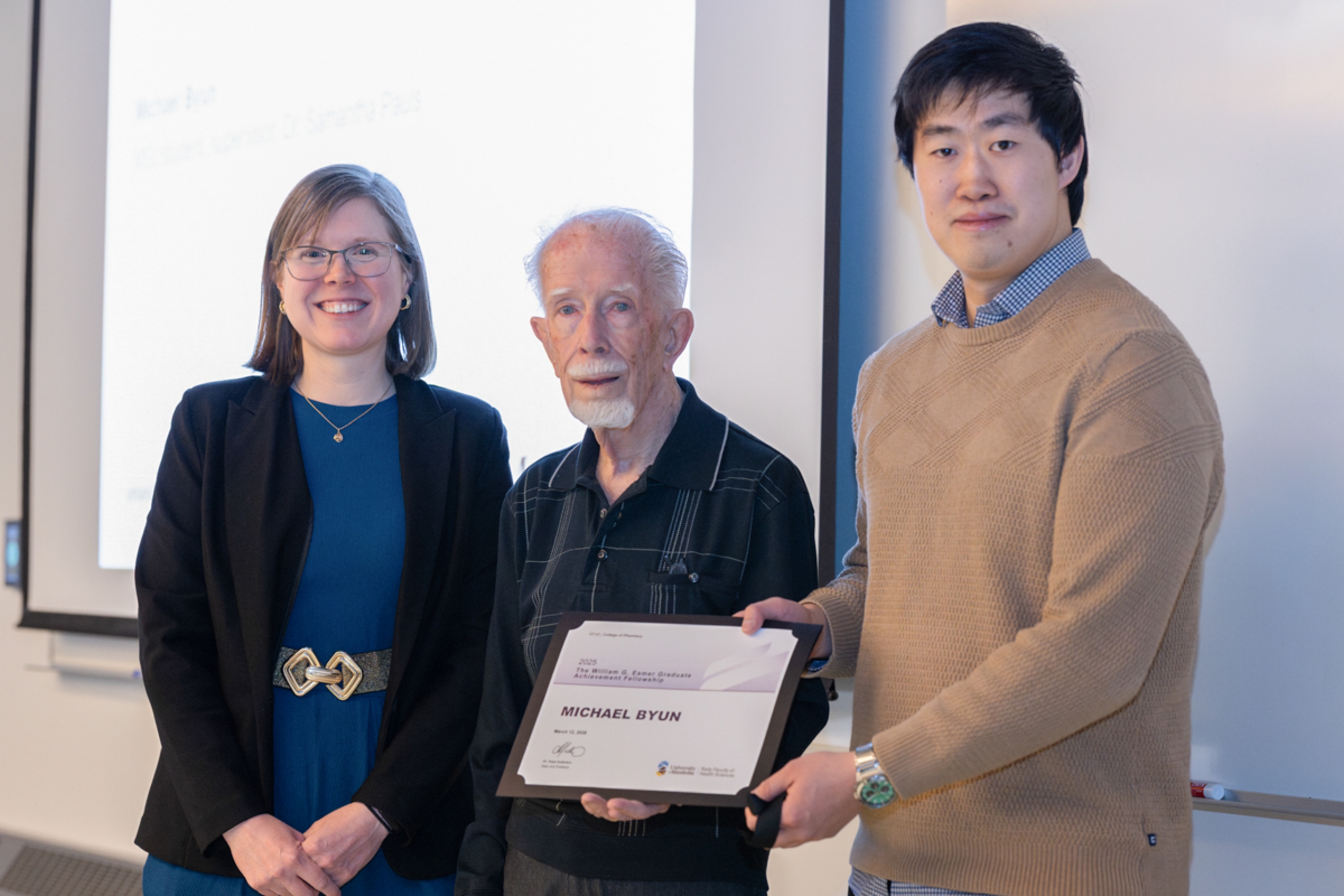 Three people hold an award certificate.