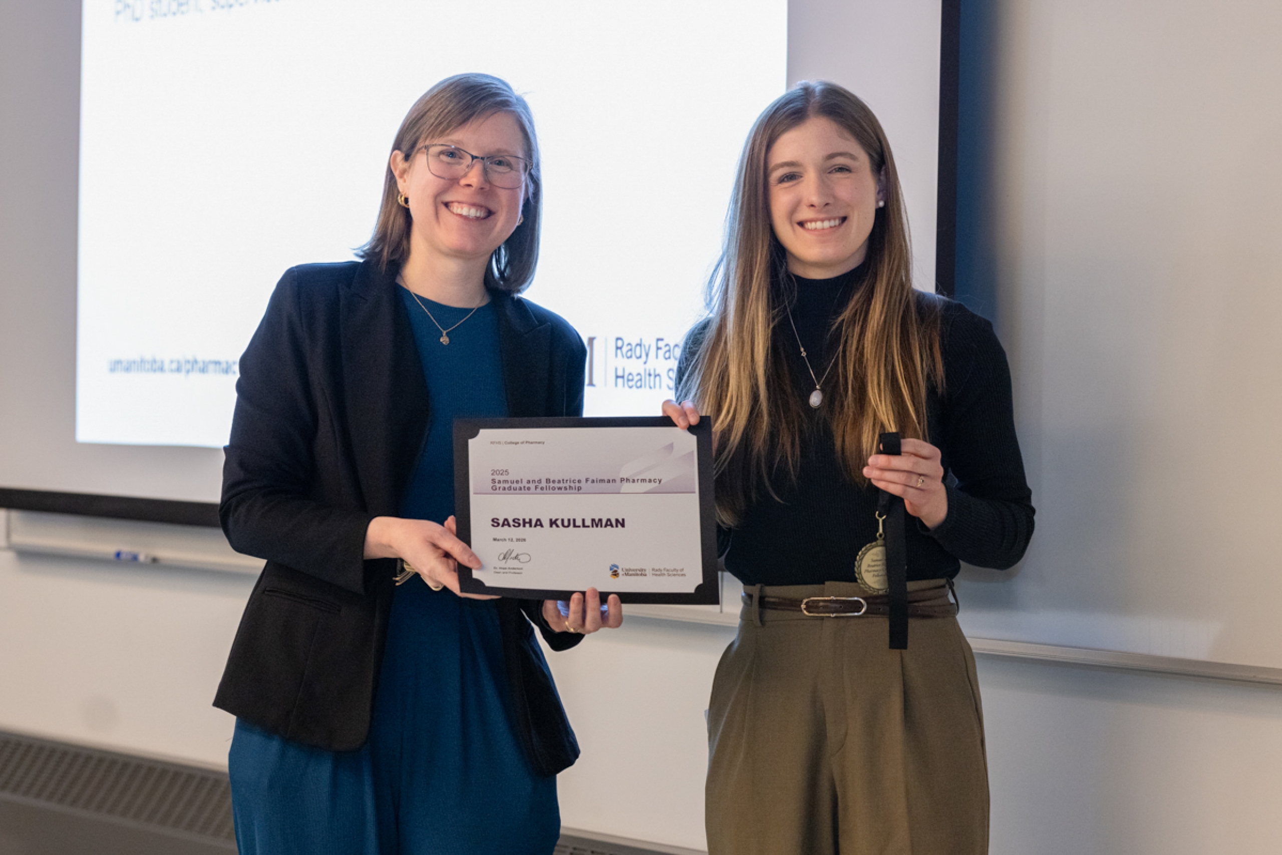 Two people holding an award certificate smile for the camera.