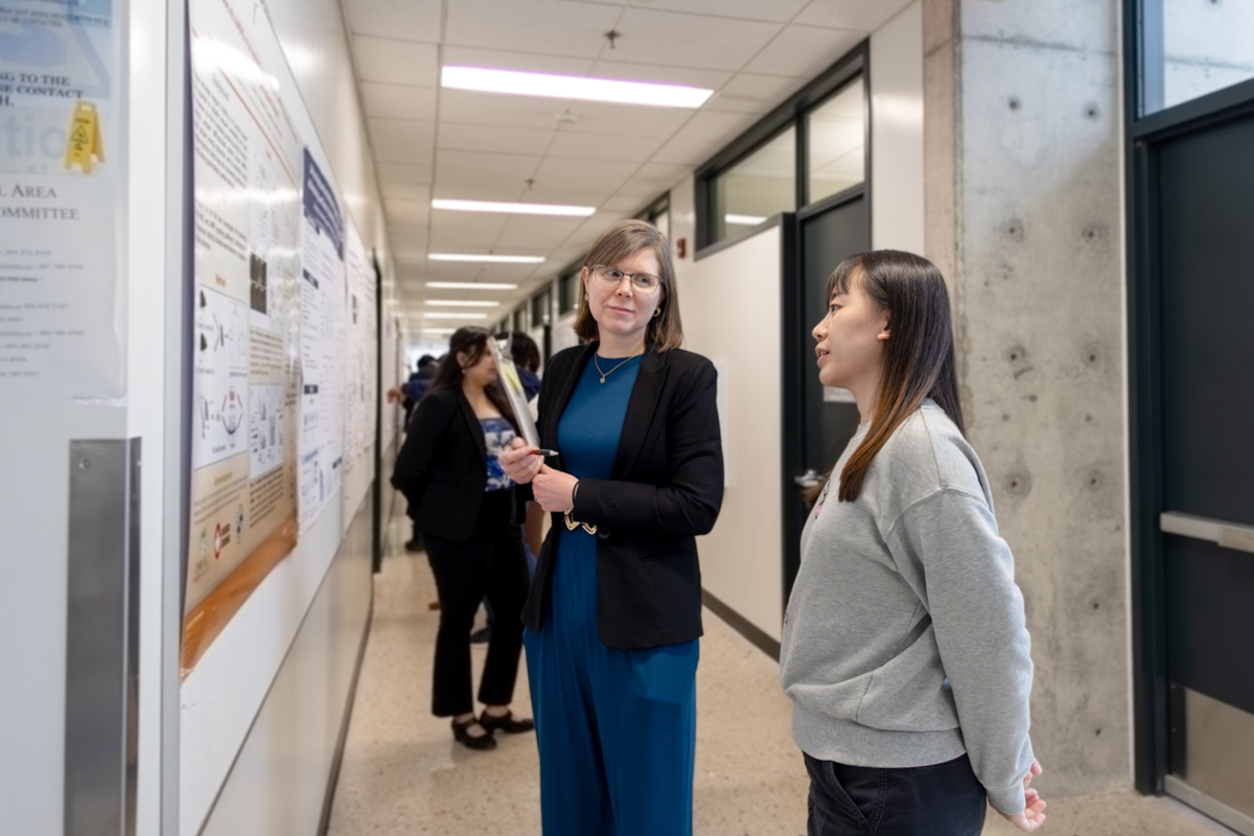 A student and a judge examine a research poster.