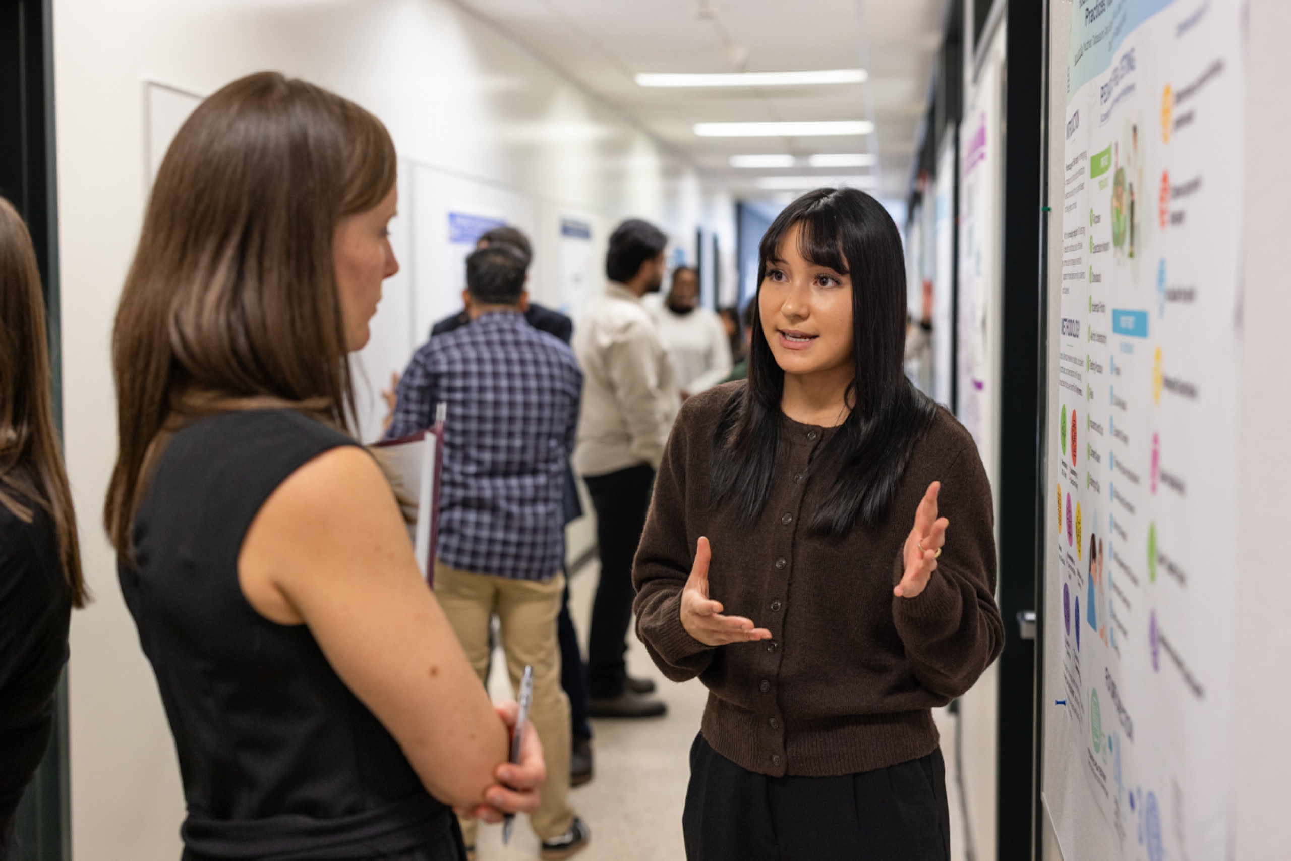 A student presenting their research on a poster to a judge.