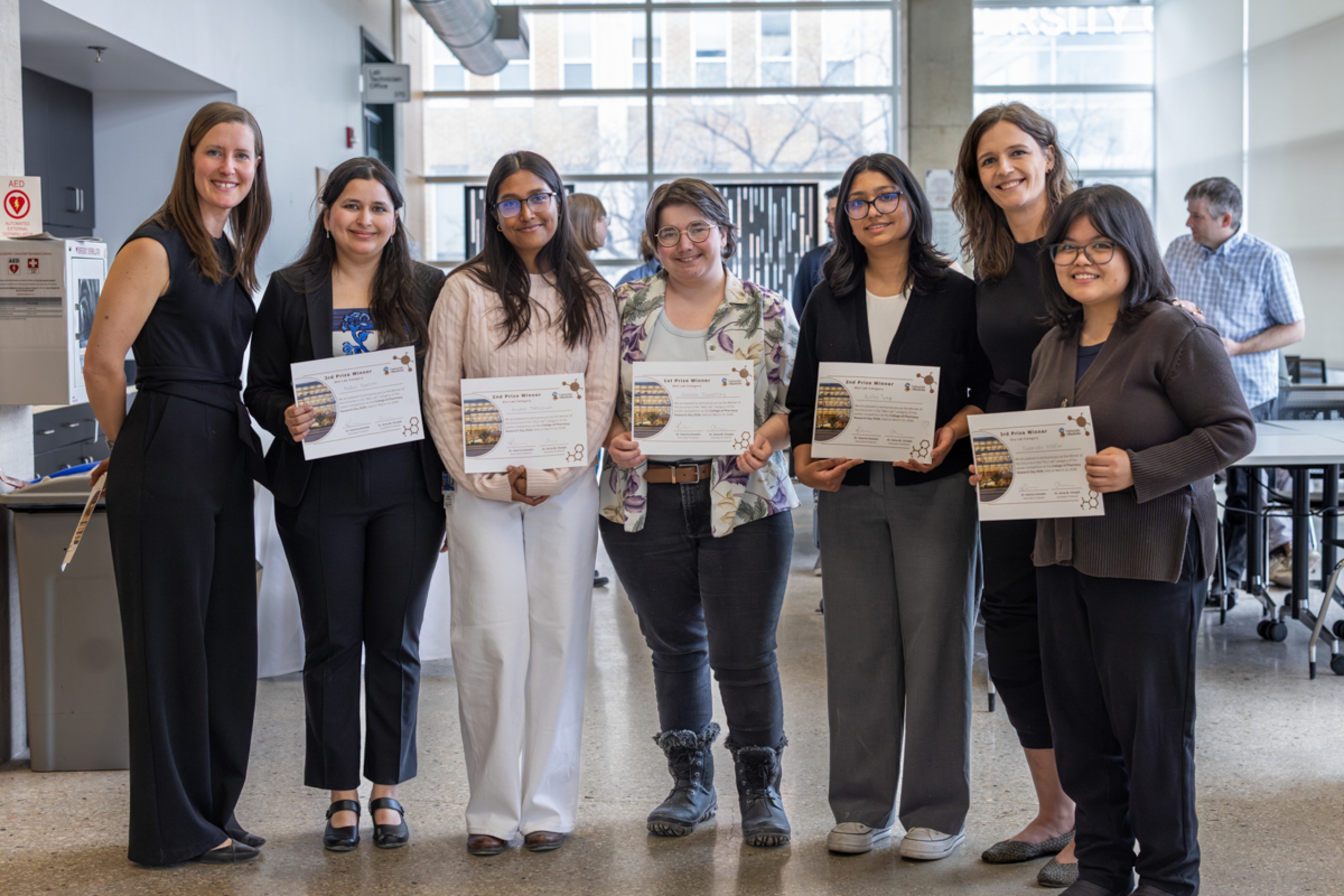 Group of seven people, five are students holding up their award certificates.