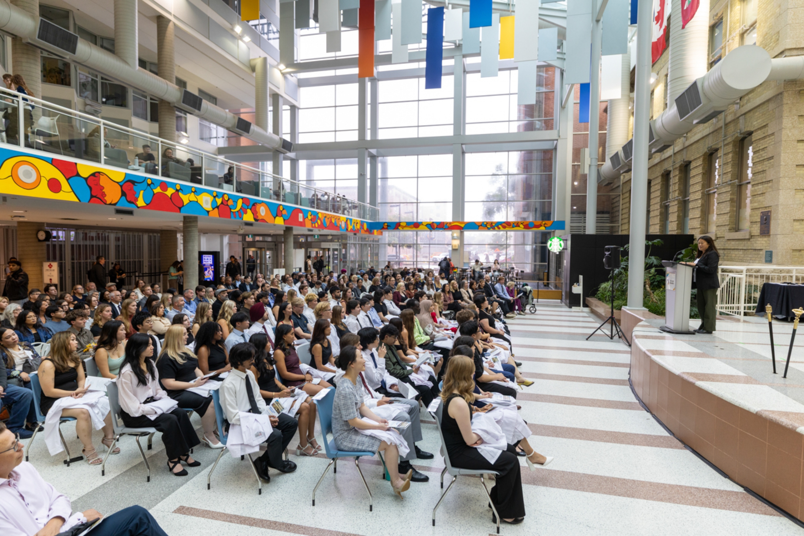 A crowd of people listening to a speech in an atrium.