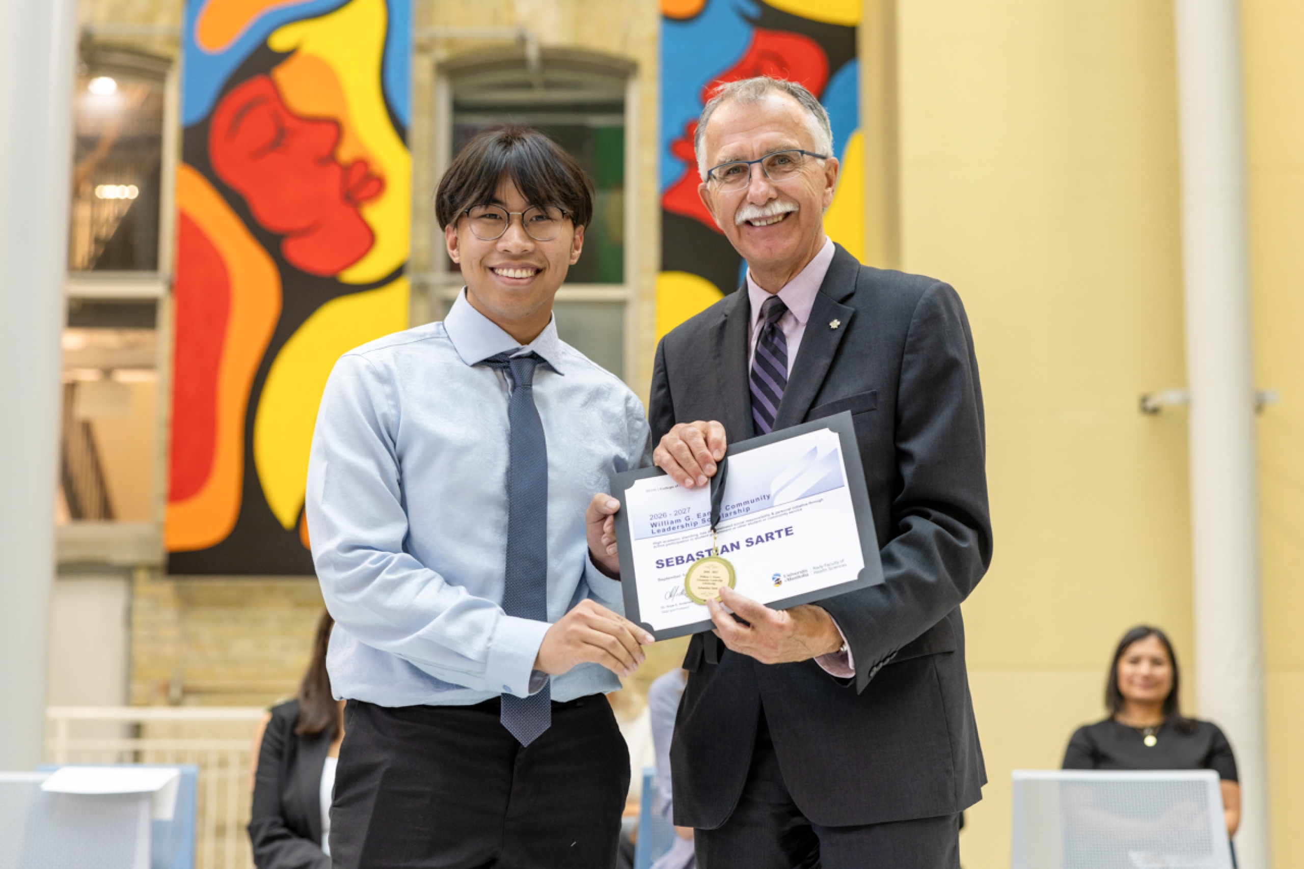 Two people holding an award certificate.