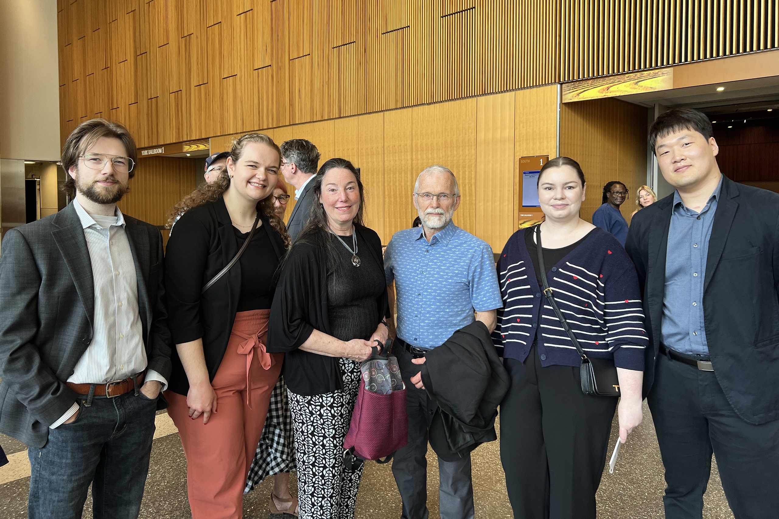 four law students stand on each side of an older couple at Winnipeg's city hall