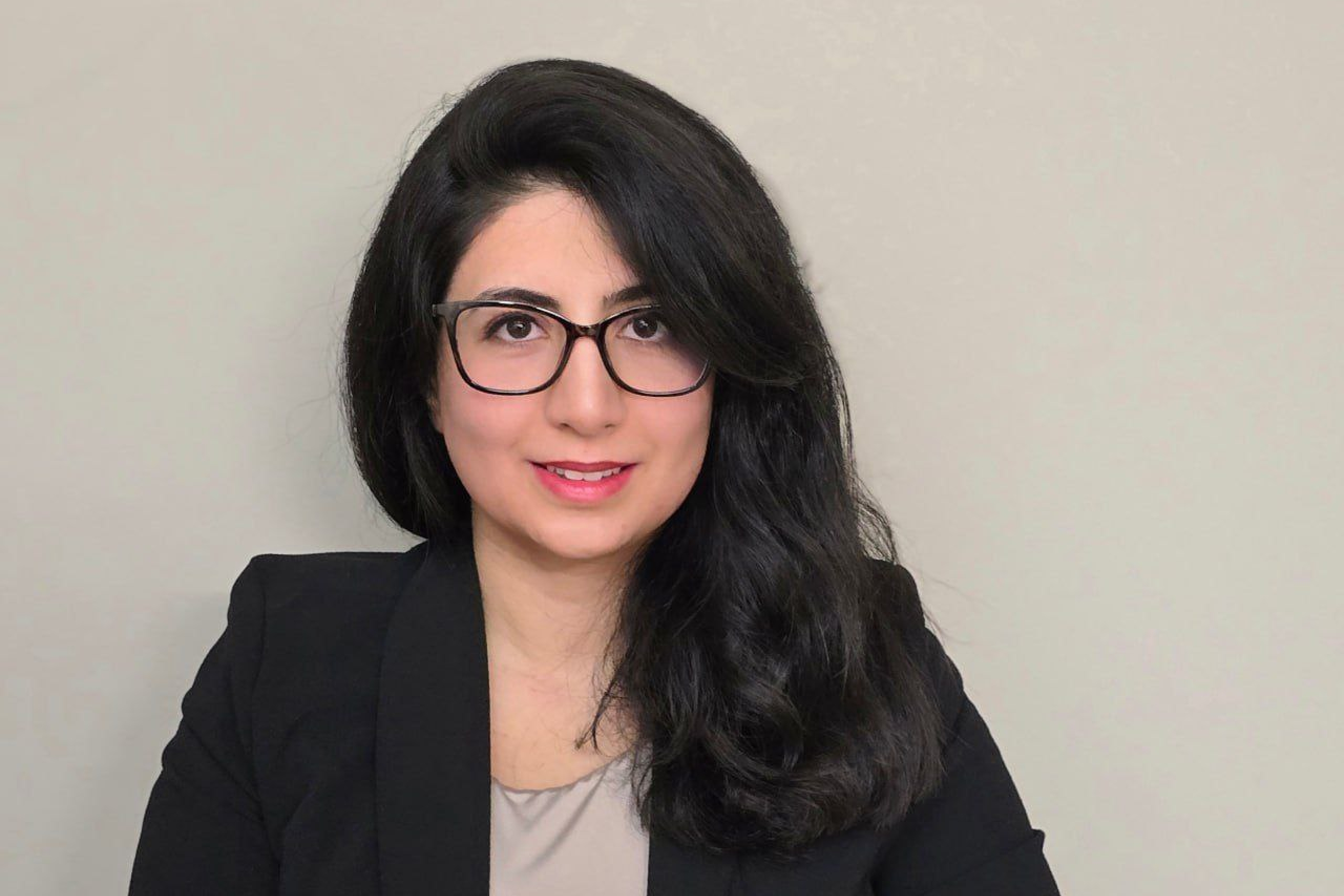 Headshot of Atefeh in black blazer and glasses, smiling.