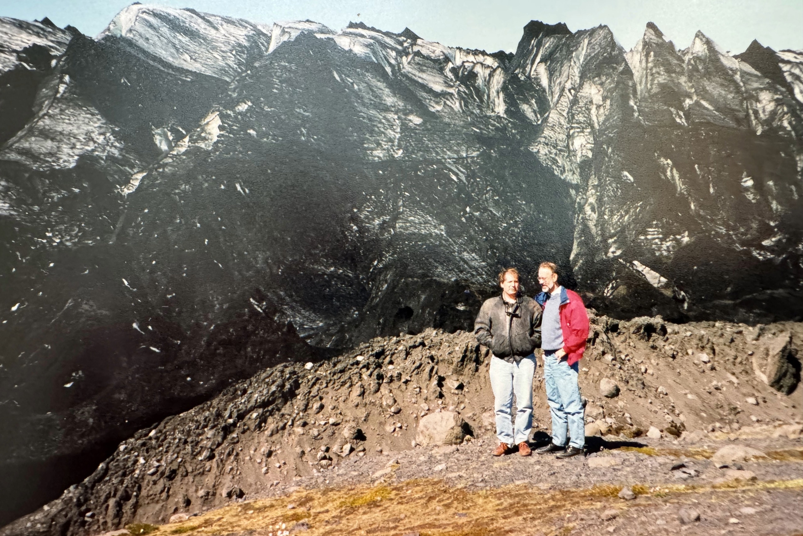 Two people stand in front of a mountain in Iceland.