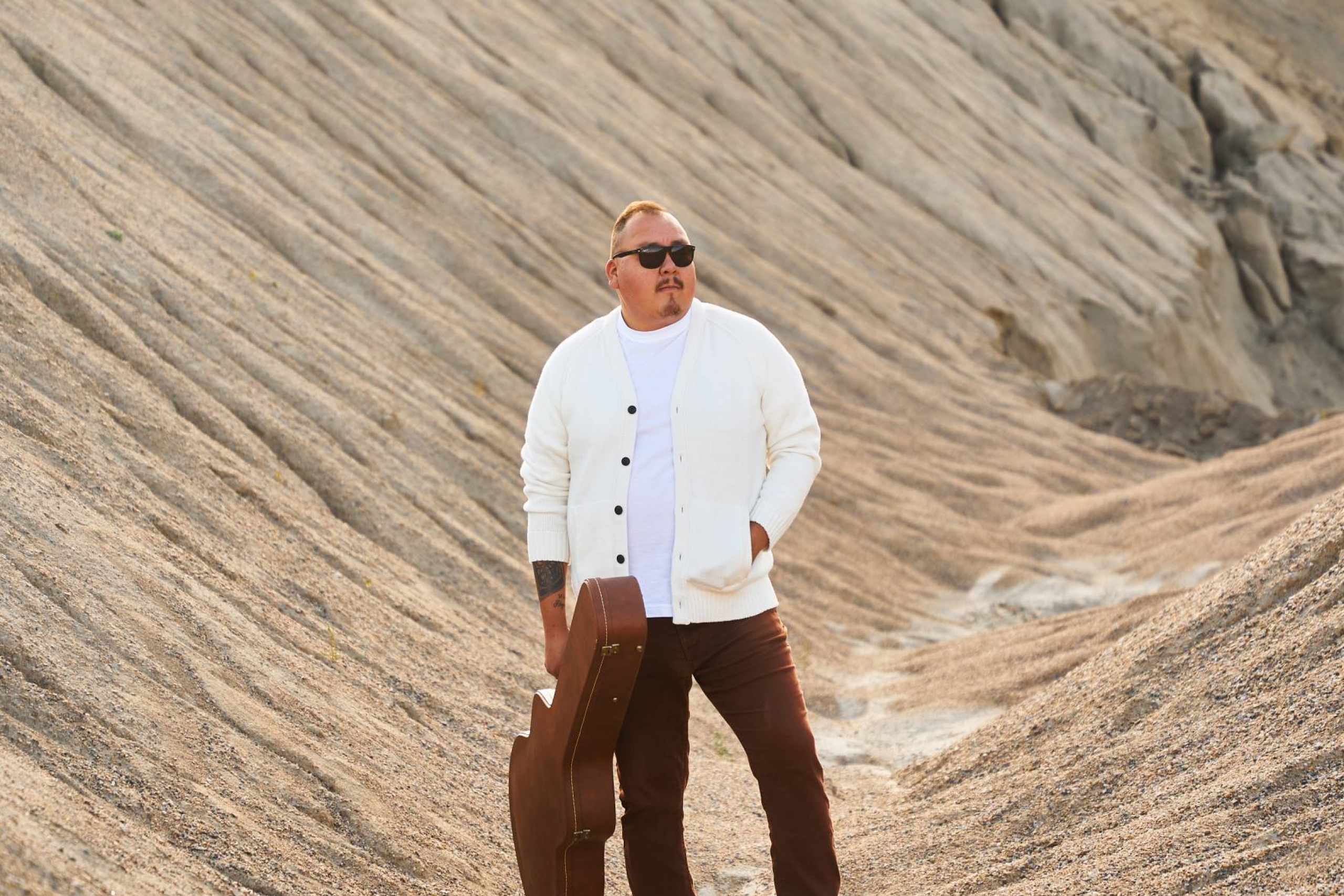 William Prince, holding a guitar case in his right hand.