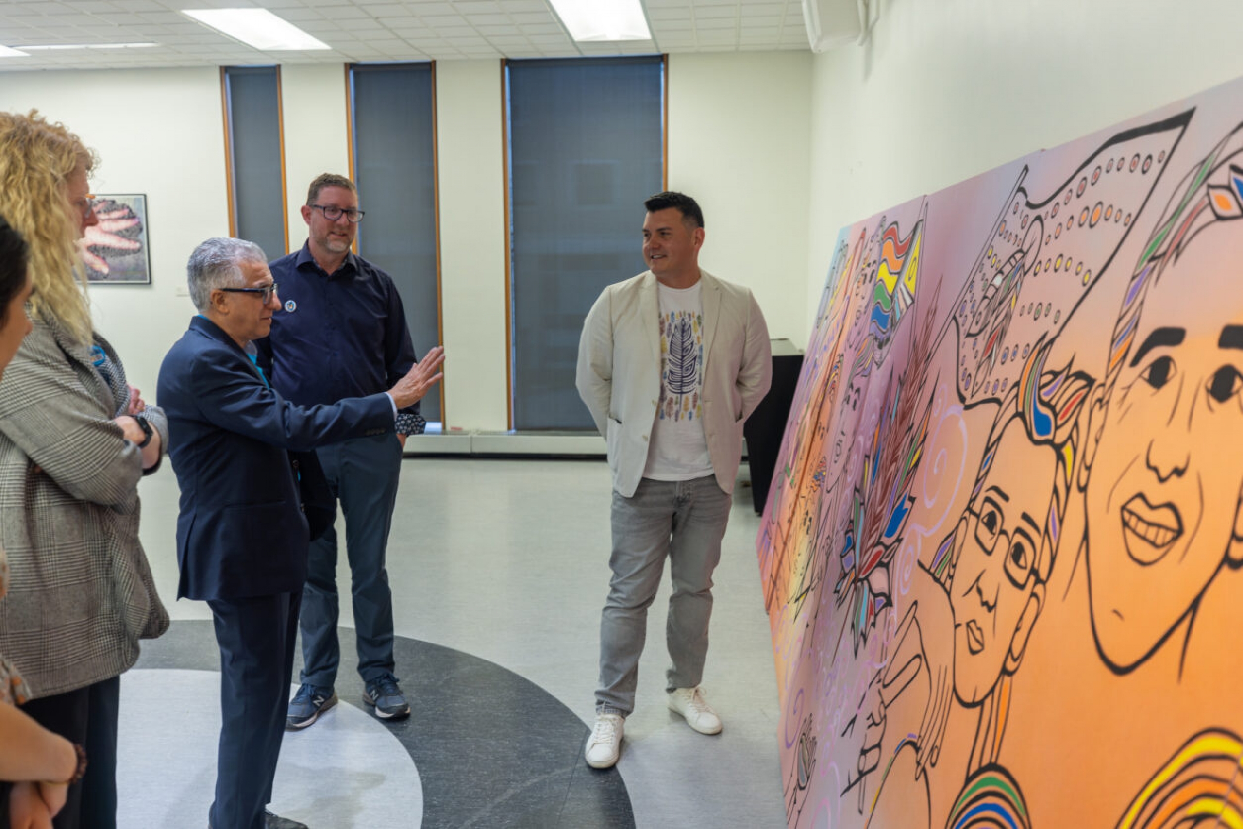 Hunter standing next to his mural as Michael Benarroch and others observe it.