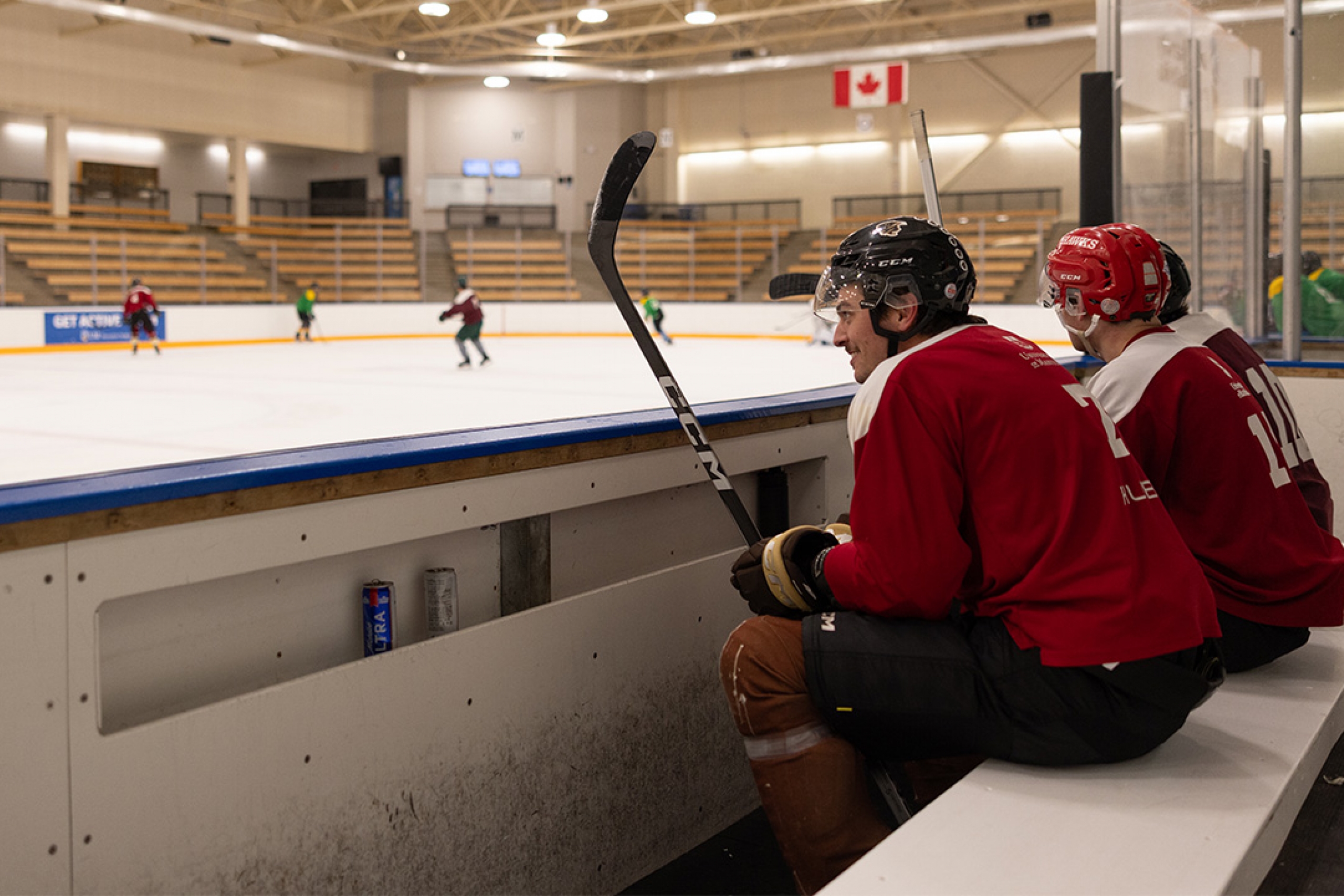 Two hockey players sitting on a bench watching a game