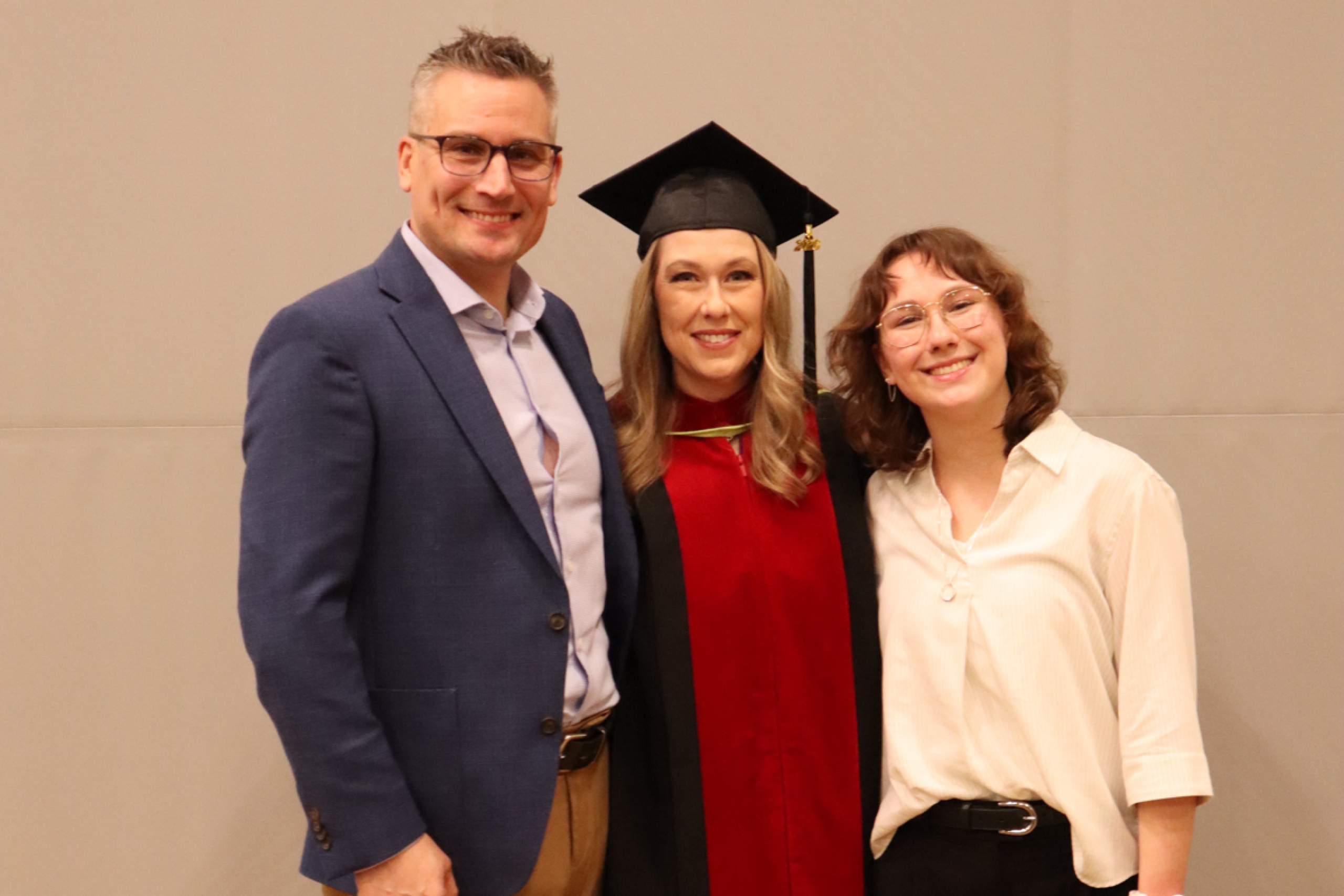 A graduate in robes with husband and daughter.