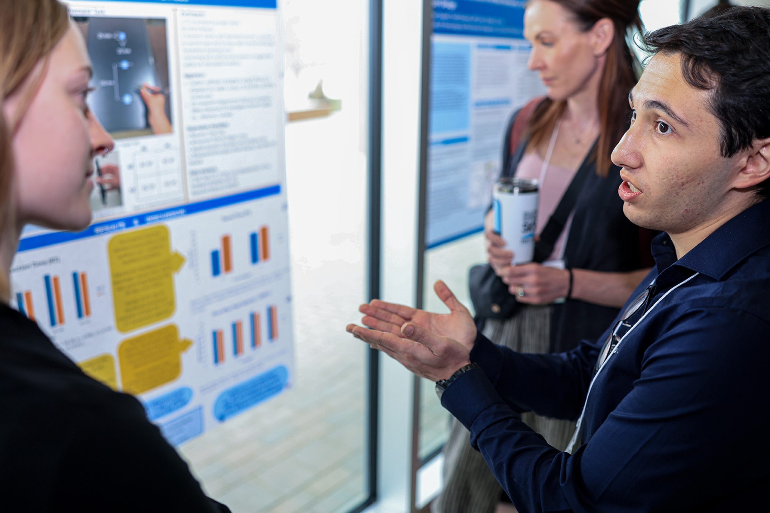 A man presenting his poster to a guest at Research Day 2026