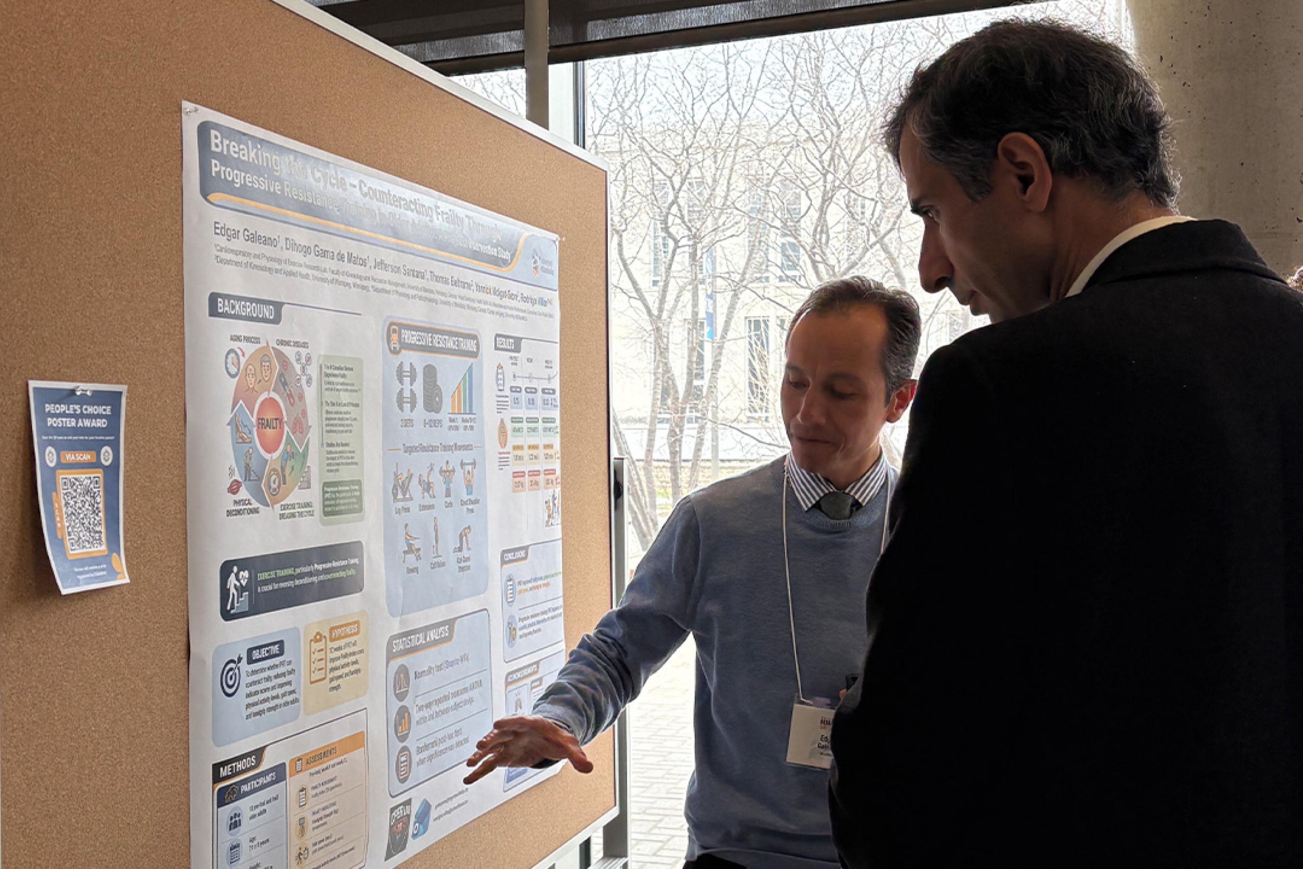 A man presenting his poster to a guest at Research Day 2026