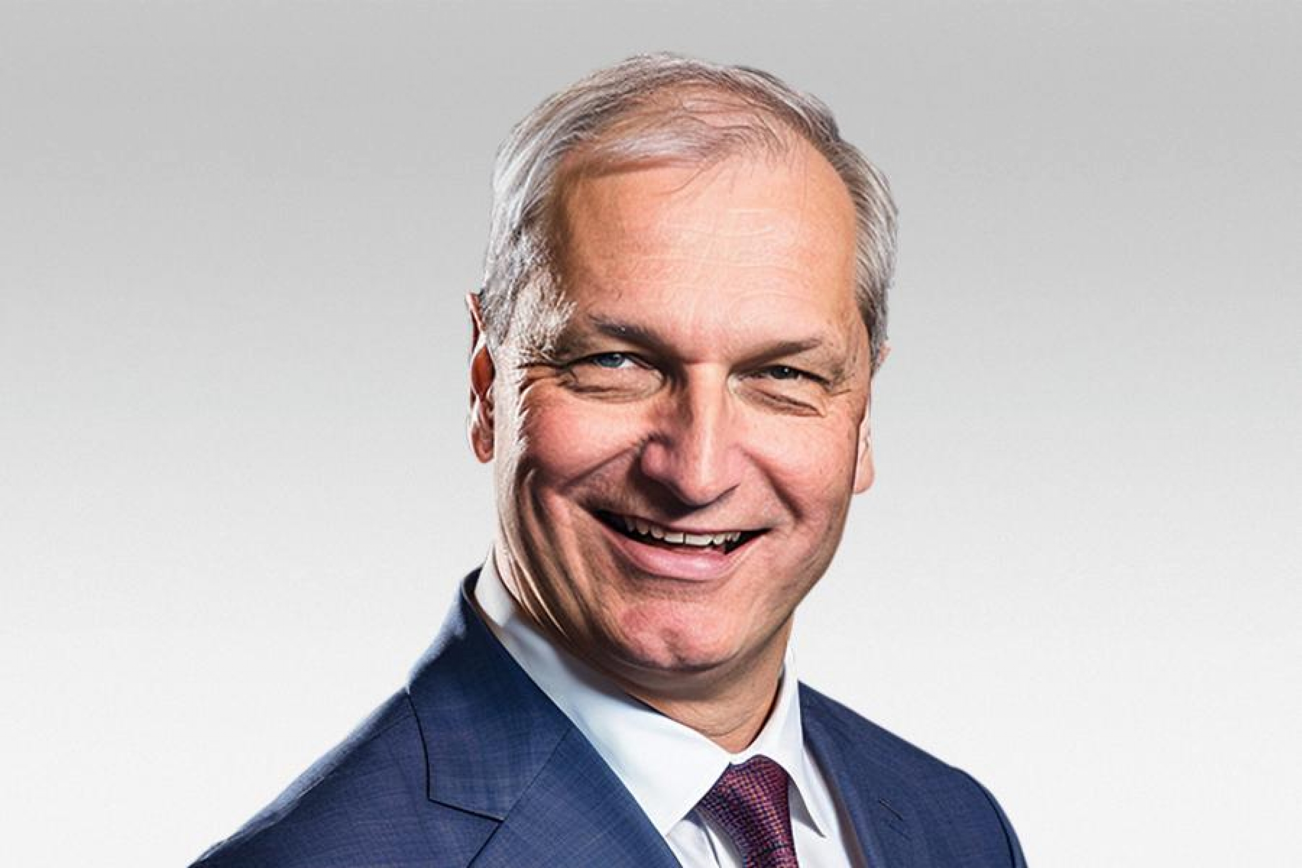 Man in a suit and tie smiling against a light background