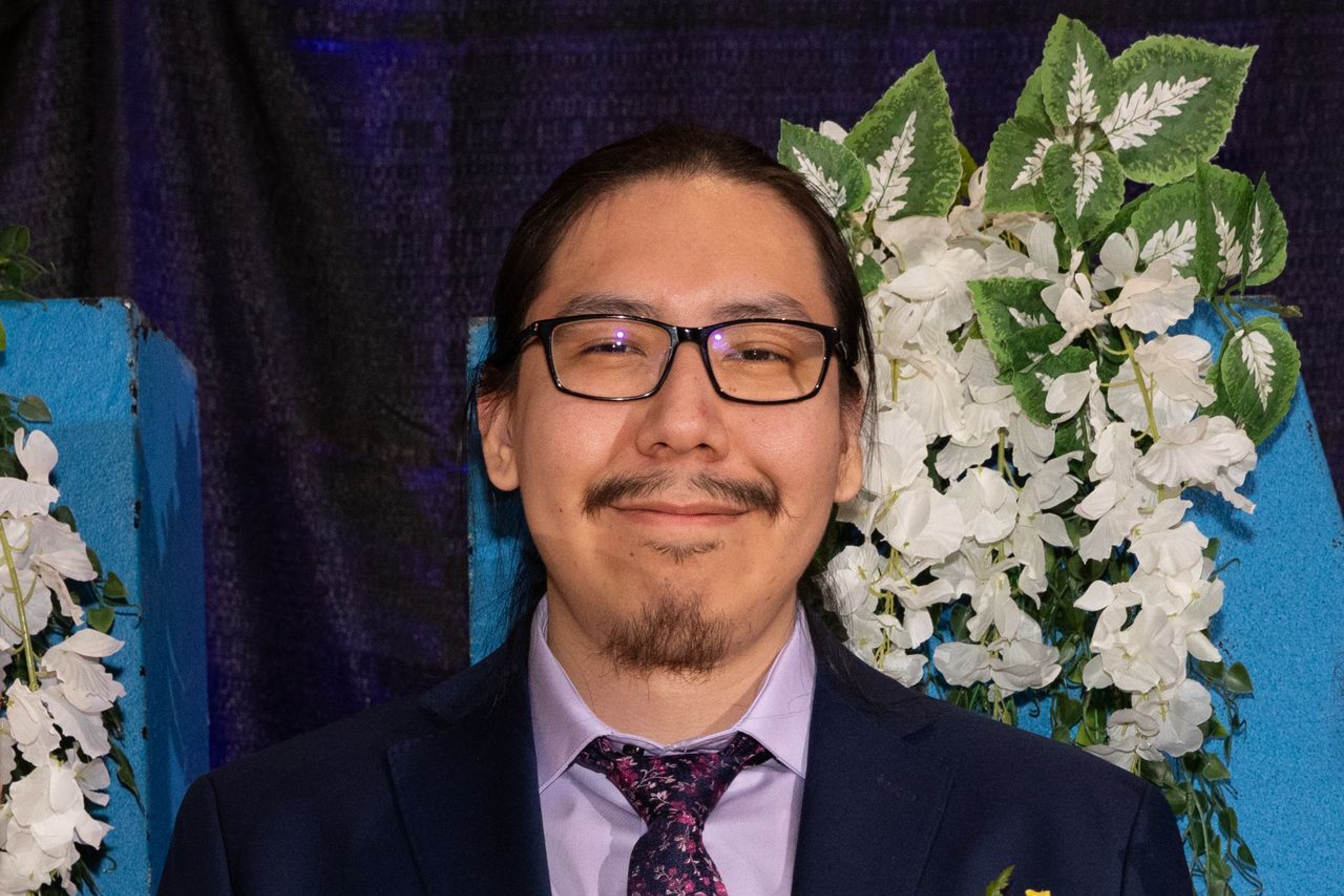 Person in formal wear posing in front of flower display