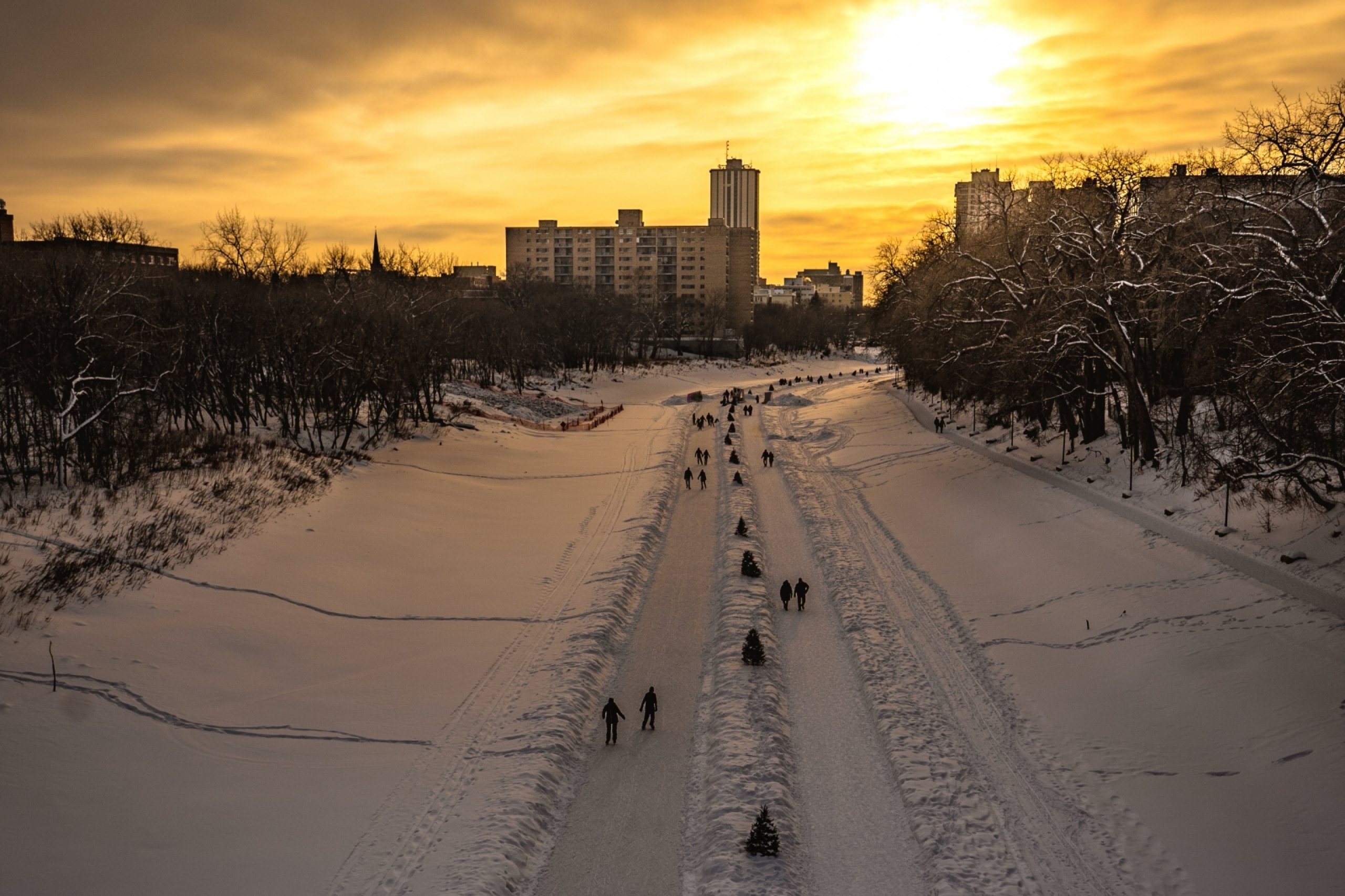 Aerial view of winter river trails. Snow is on the ground and the sun is just above the horizon.