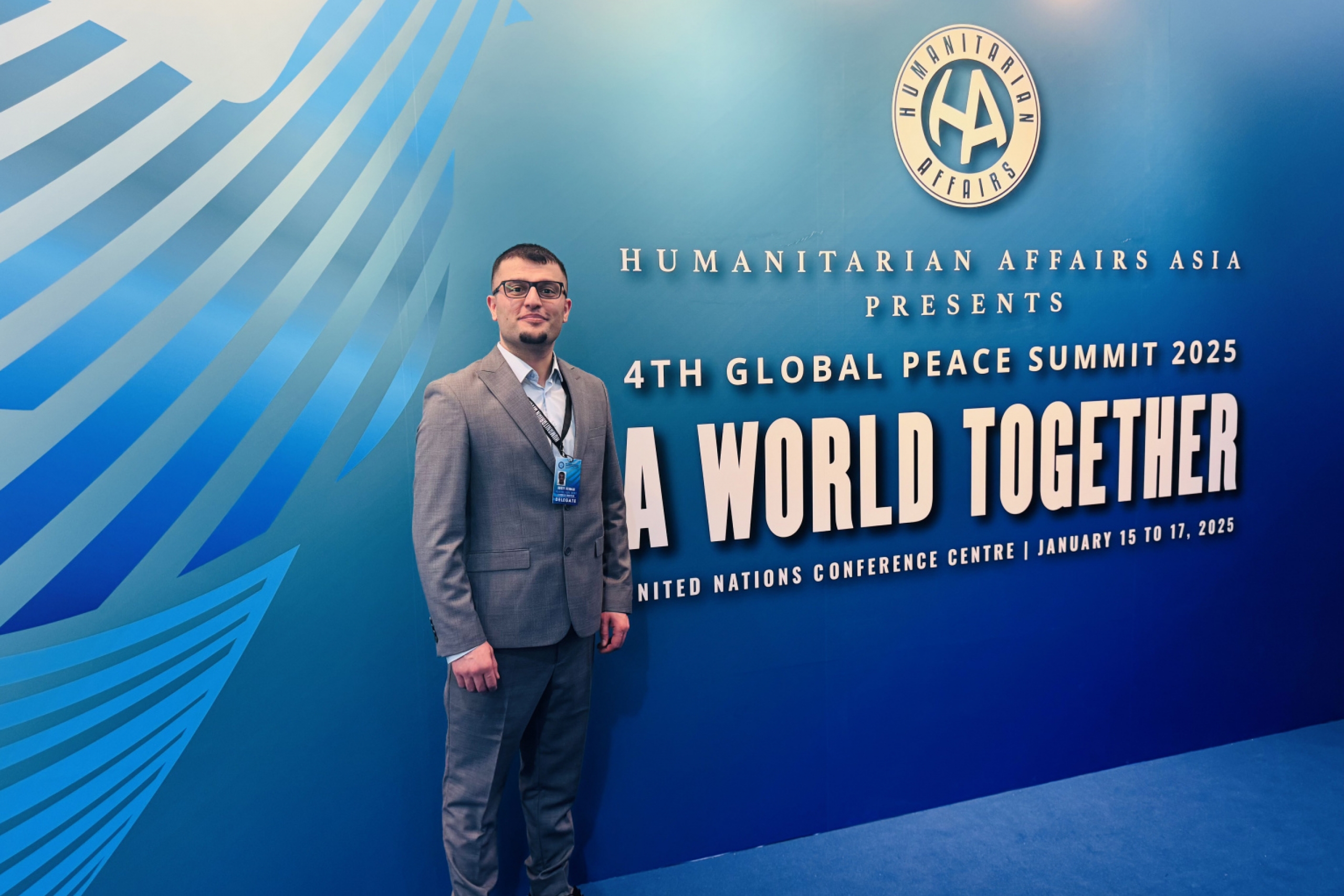 Rosty Othman standing in front of the Global Peace Summit sign