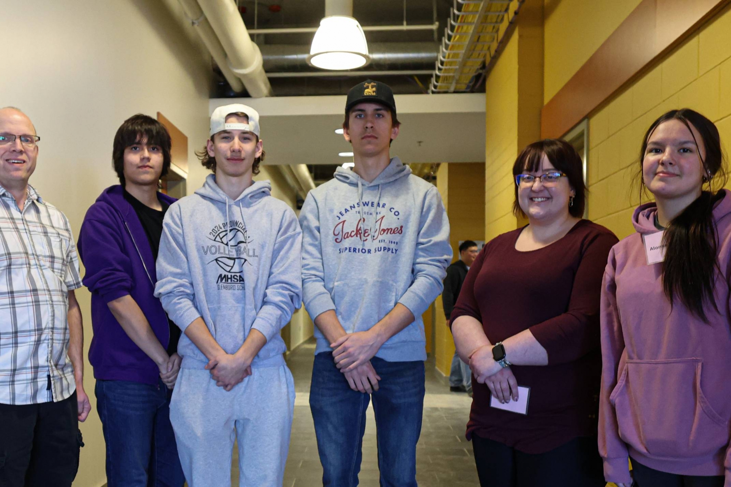 Six casually dressed people standing in a hallway.