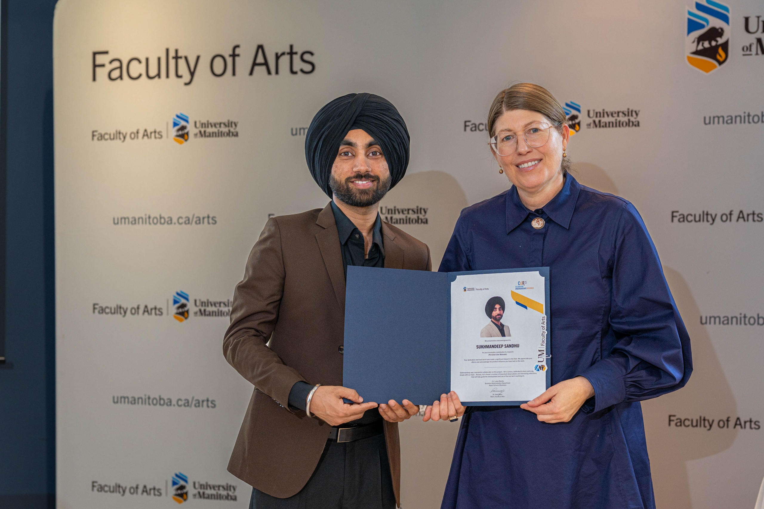 Male student and female professor posing for the camera. Student is receiving a certificate.