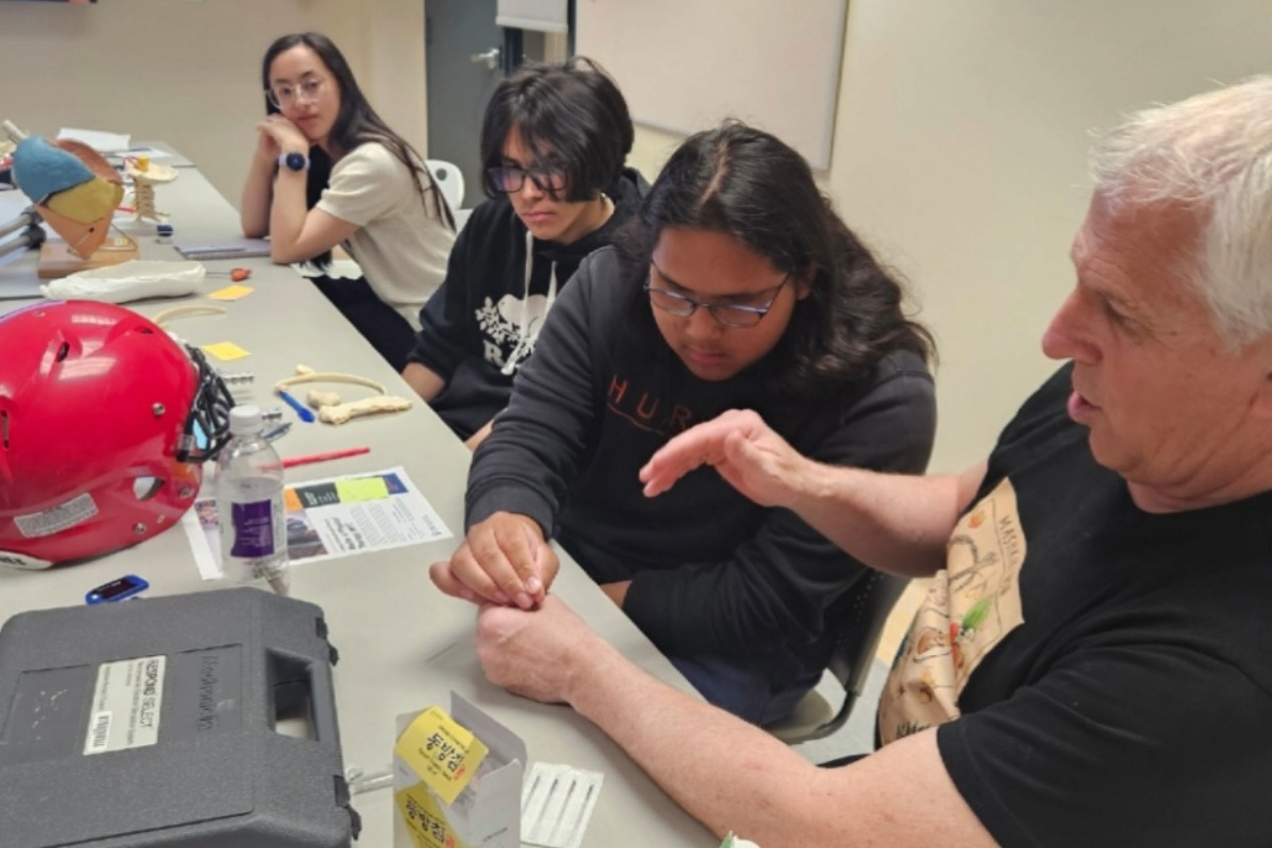 A person inserts an acupuncture needle into an instructor's hand.