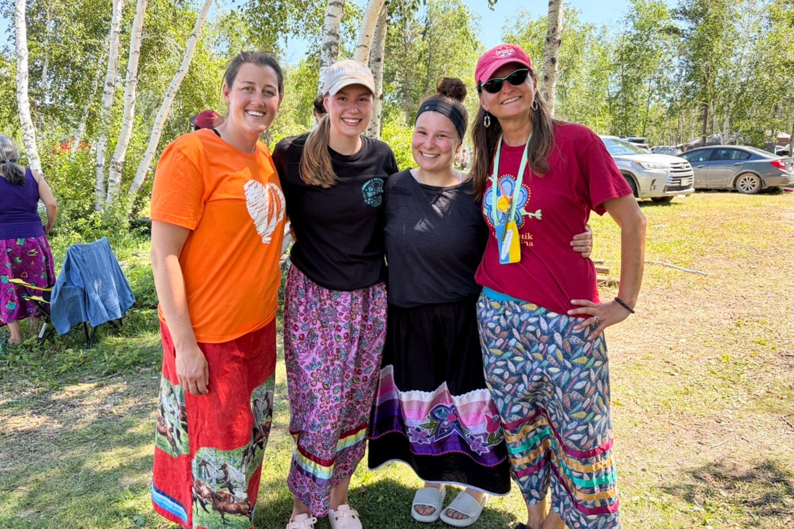 Group of photo of four people in ribbon skirts.