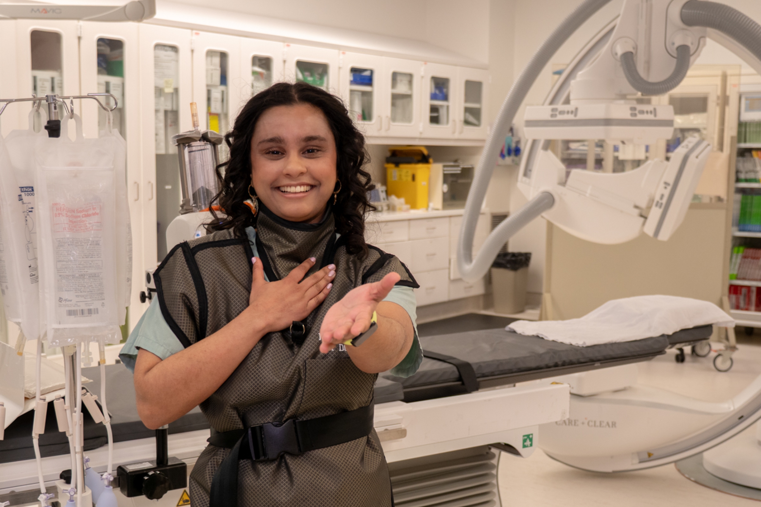 A person smiles and strikes the Give to Gain pose in an operating room.