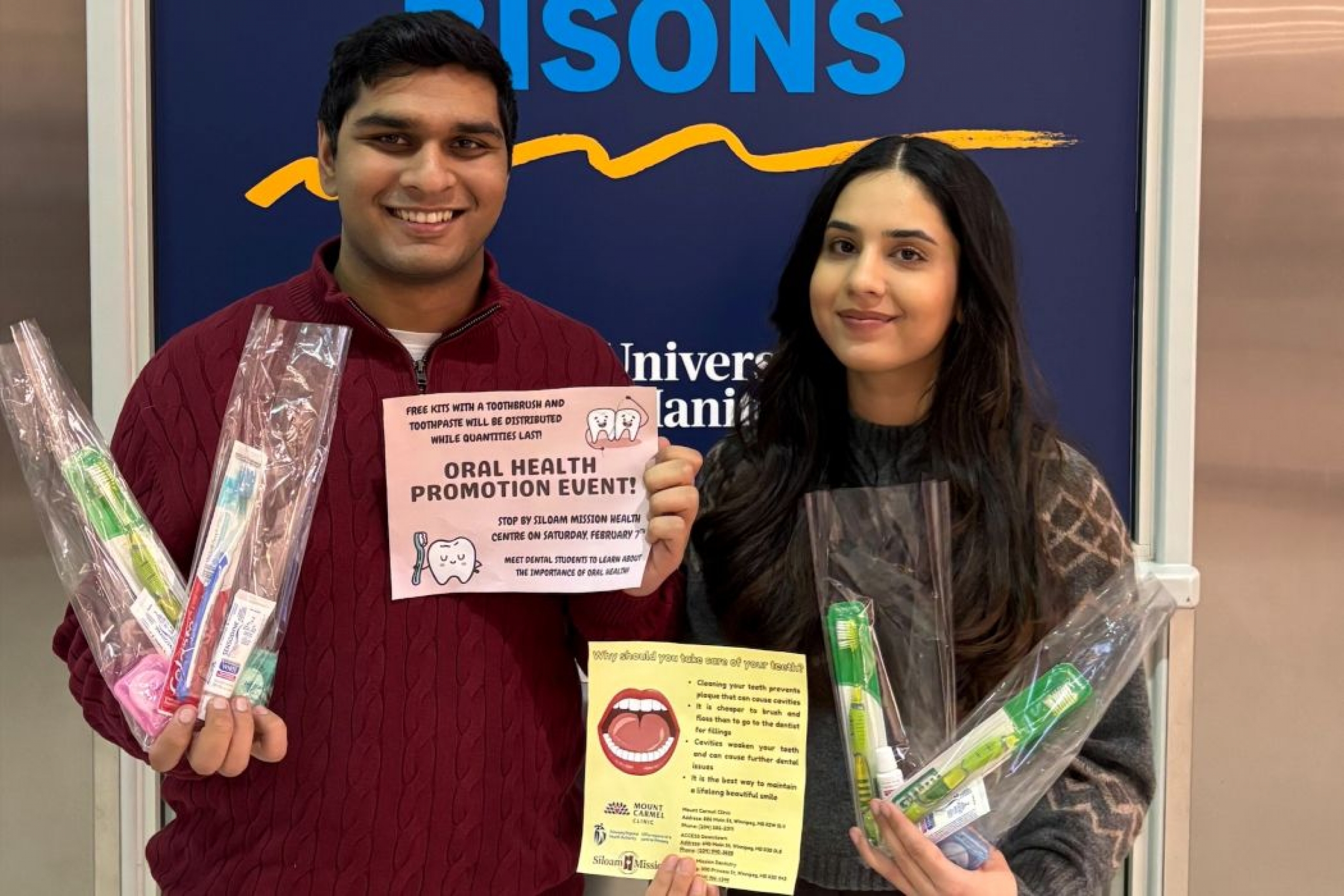 Two students hold dental hygiene kits each and oral health signs. 