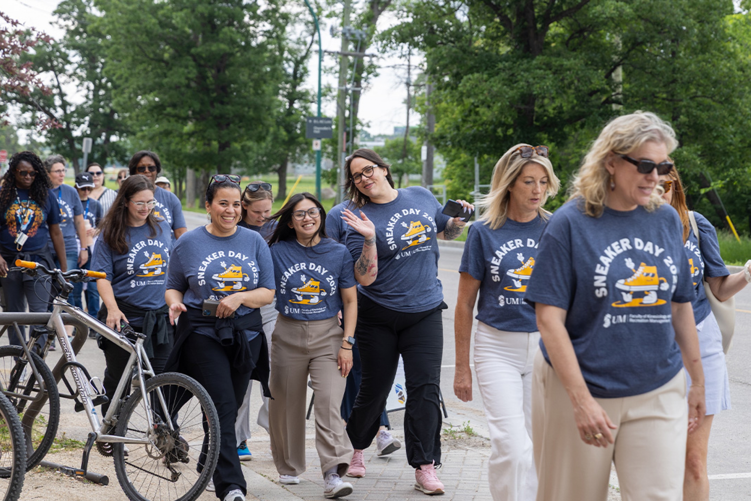 A group of women smiling and waving during the Sneaker Day walk