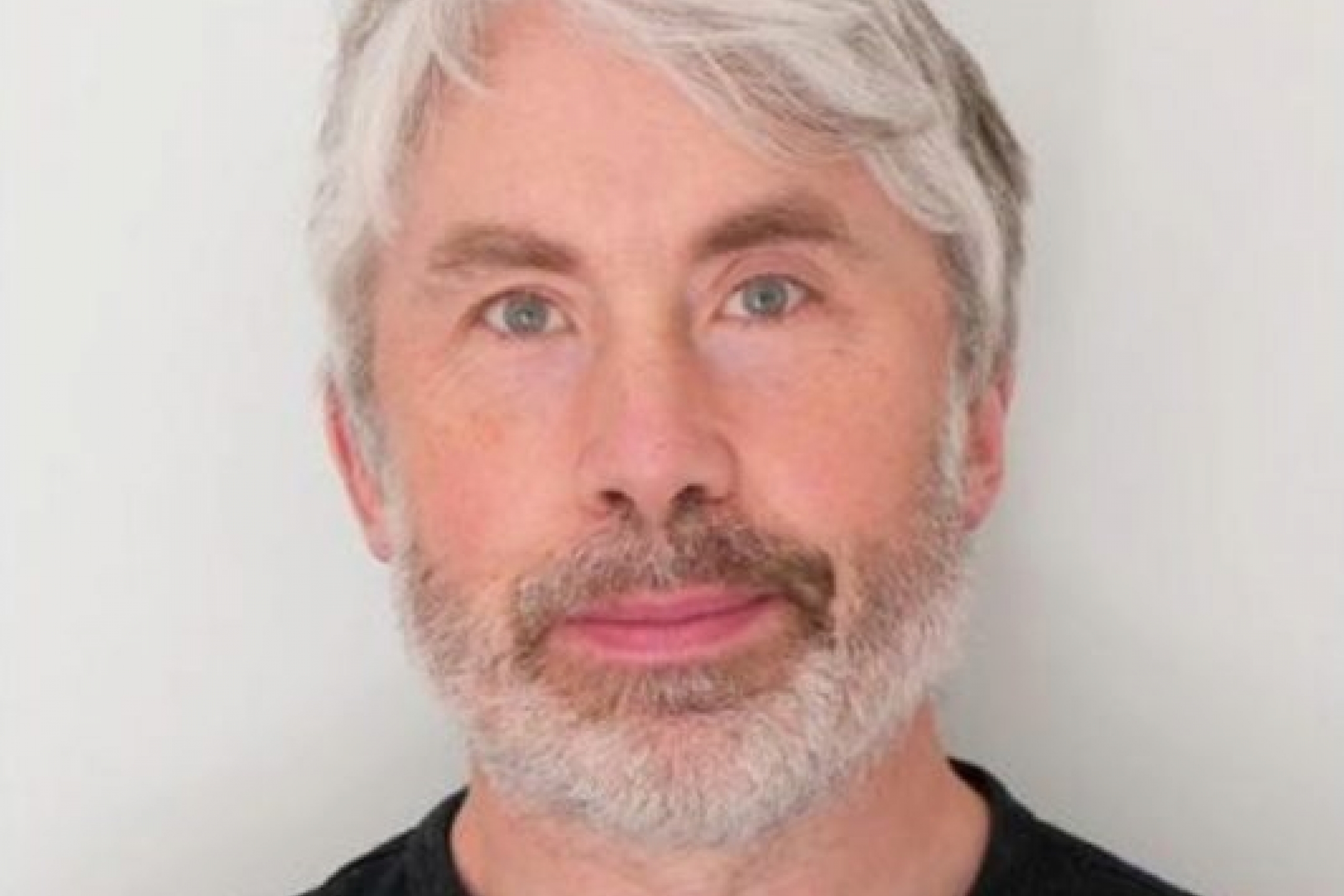 A smiling man with white hair 