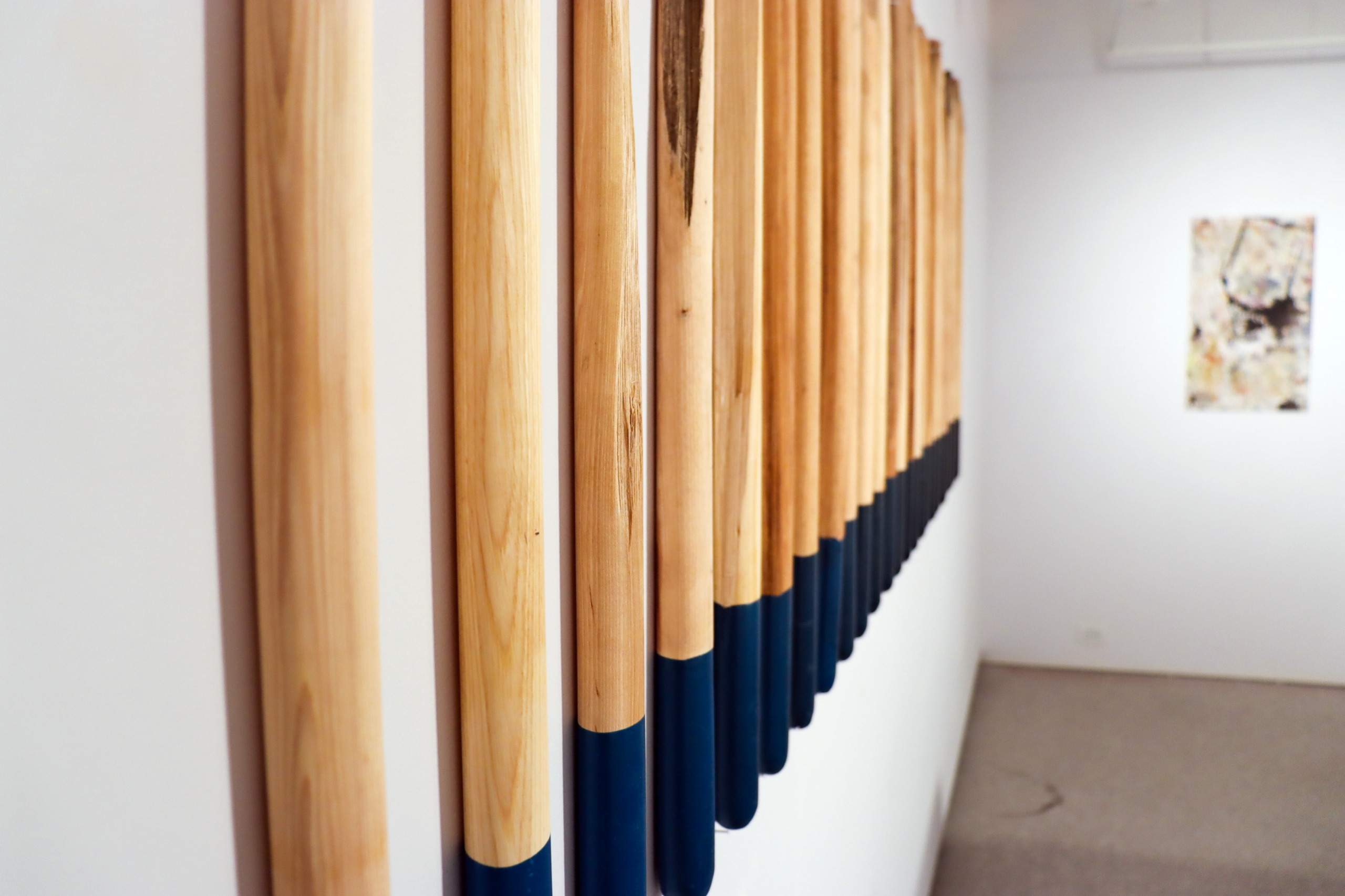 Detail of wooden poles mounted on the wall, partially dipped in dark blue.