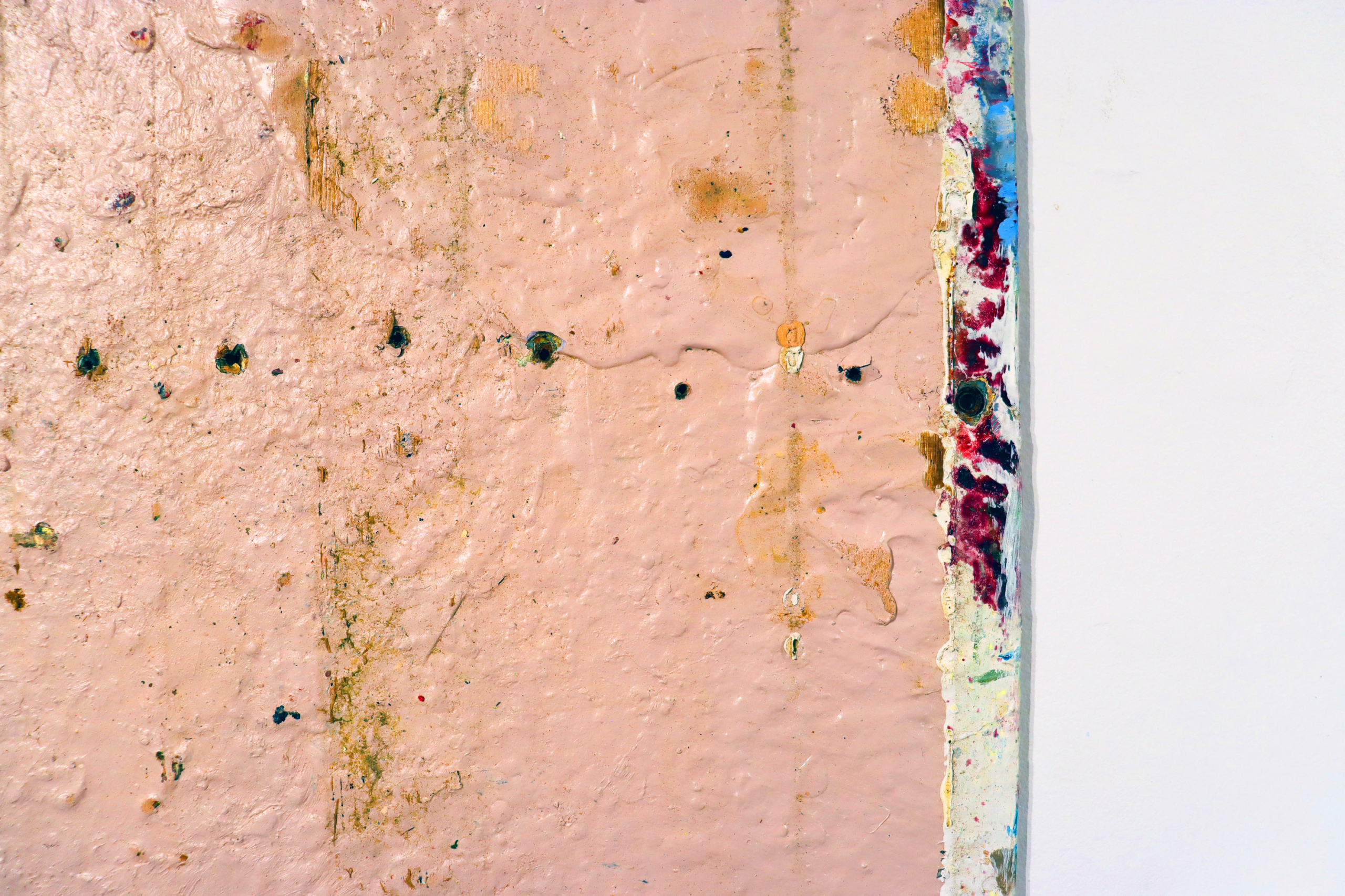 Close-up of a textured painting surface showing layered paint, stains, and material traces.