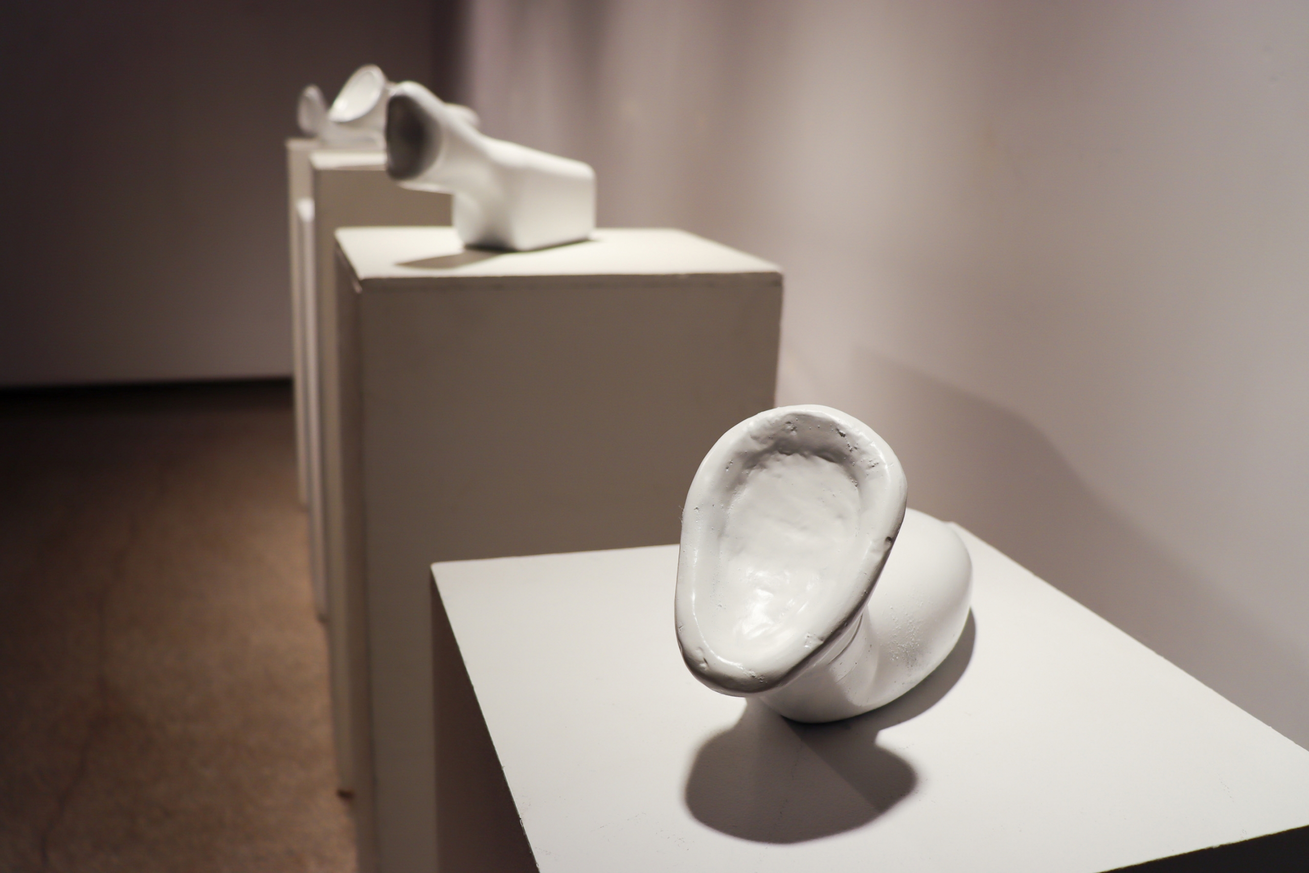 White sculptural ceramic forms displayed on plinths in the gallery.
