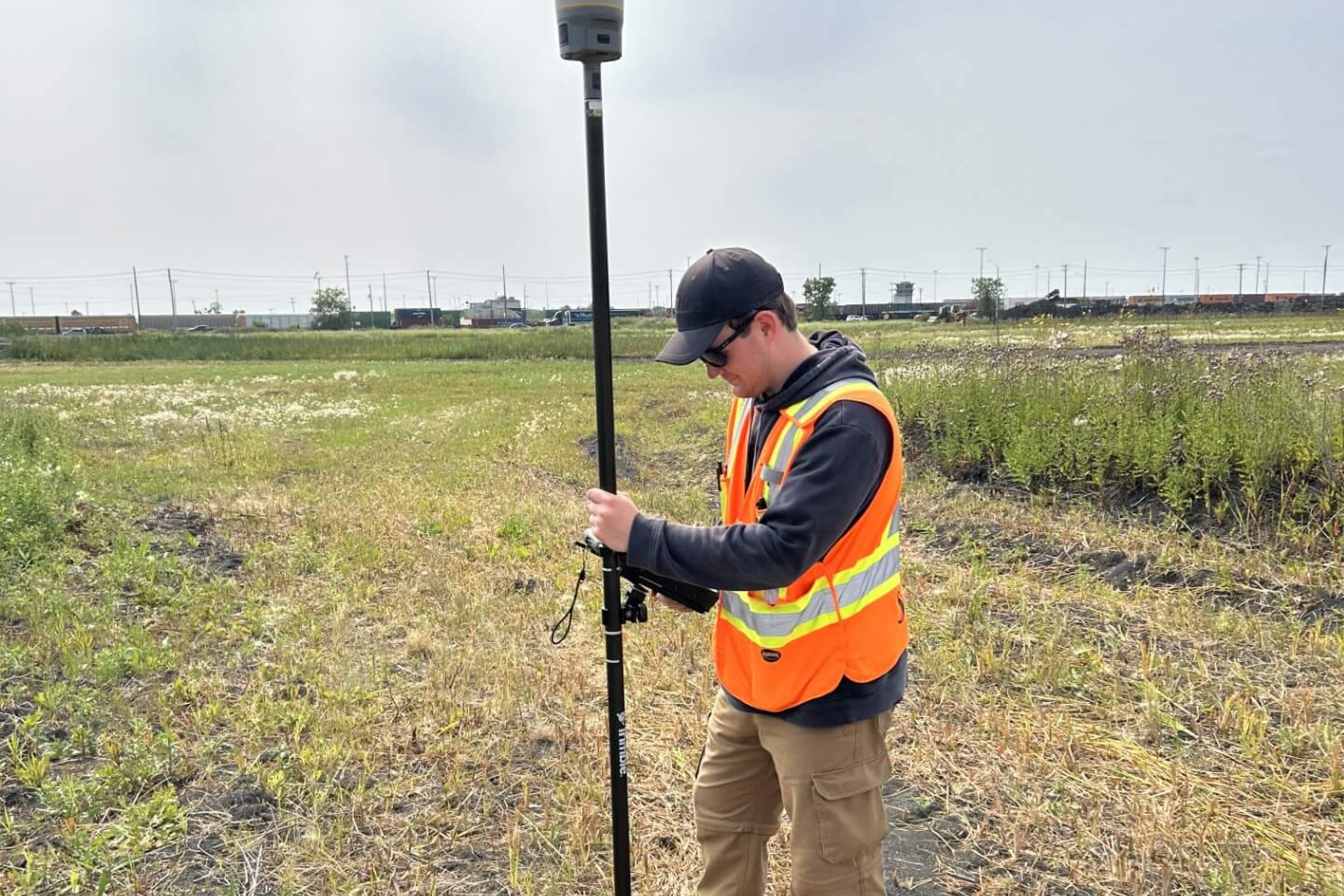 person in field wearing hard hat and safety vest