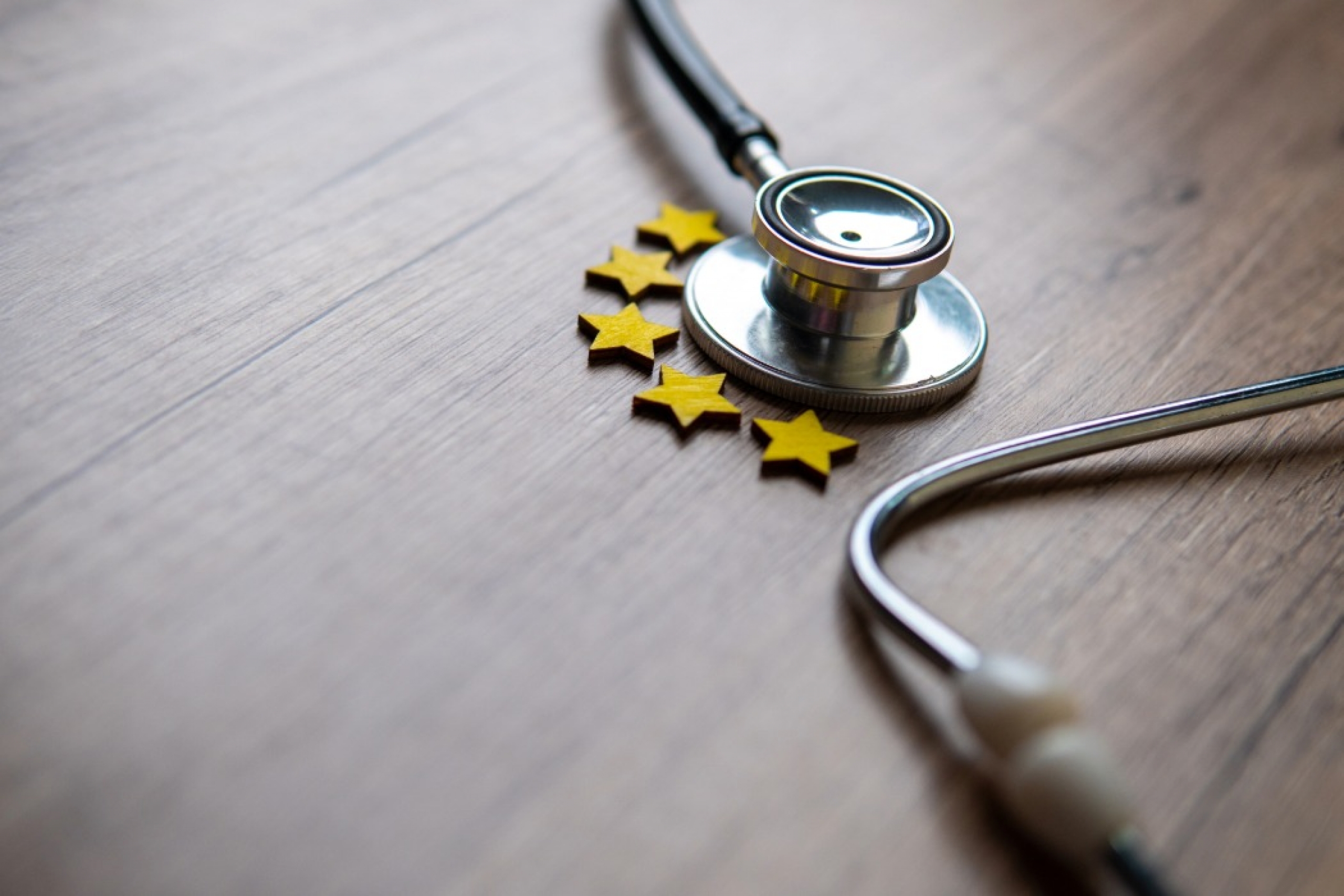 Closeup image of stethoscope and five stars on wooden table.