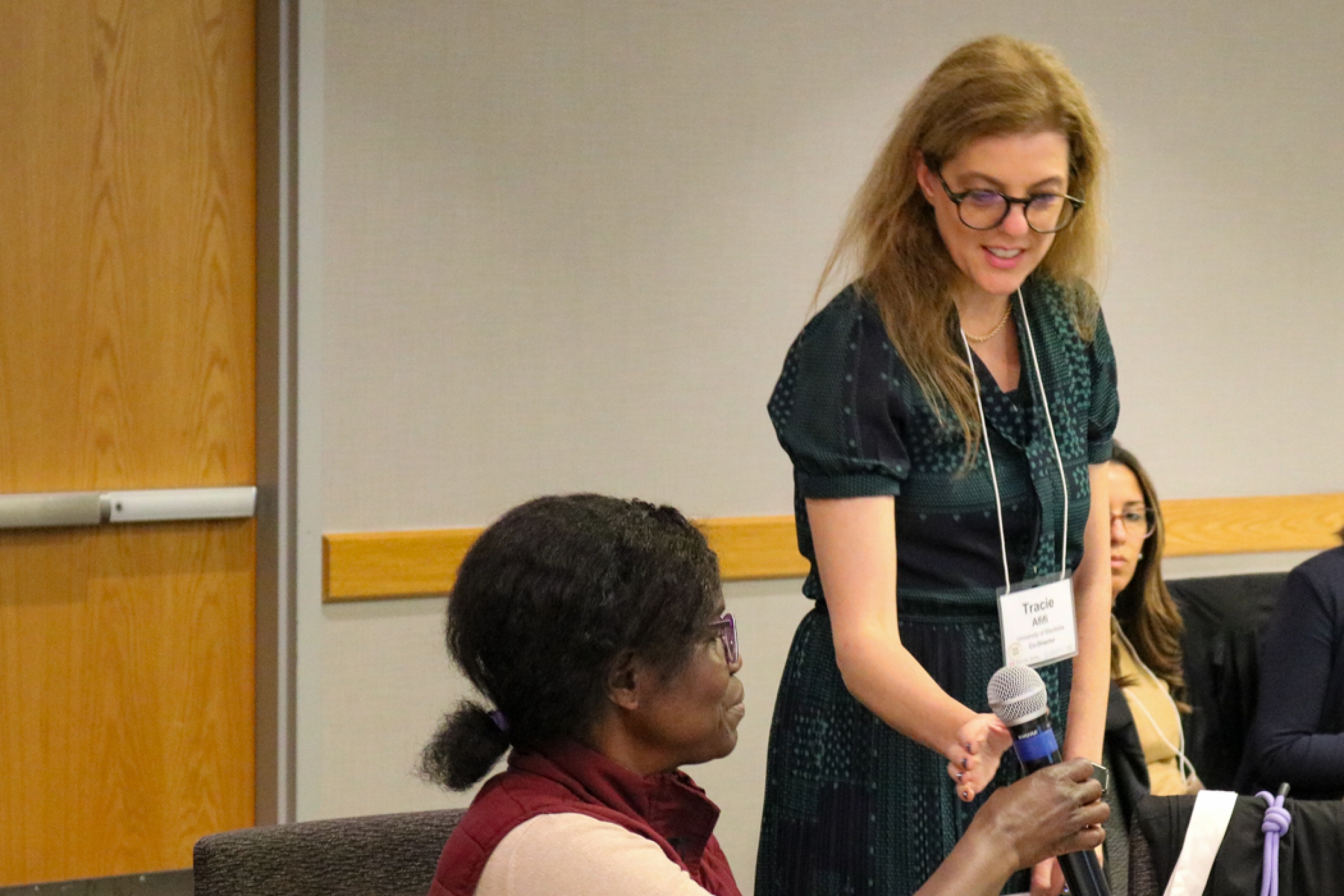 Person sitting passing microphone to person standing.