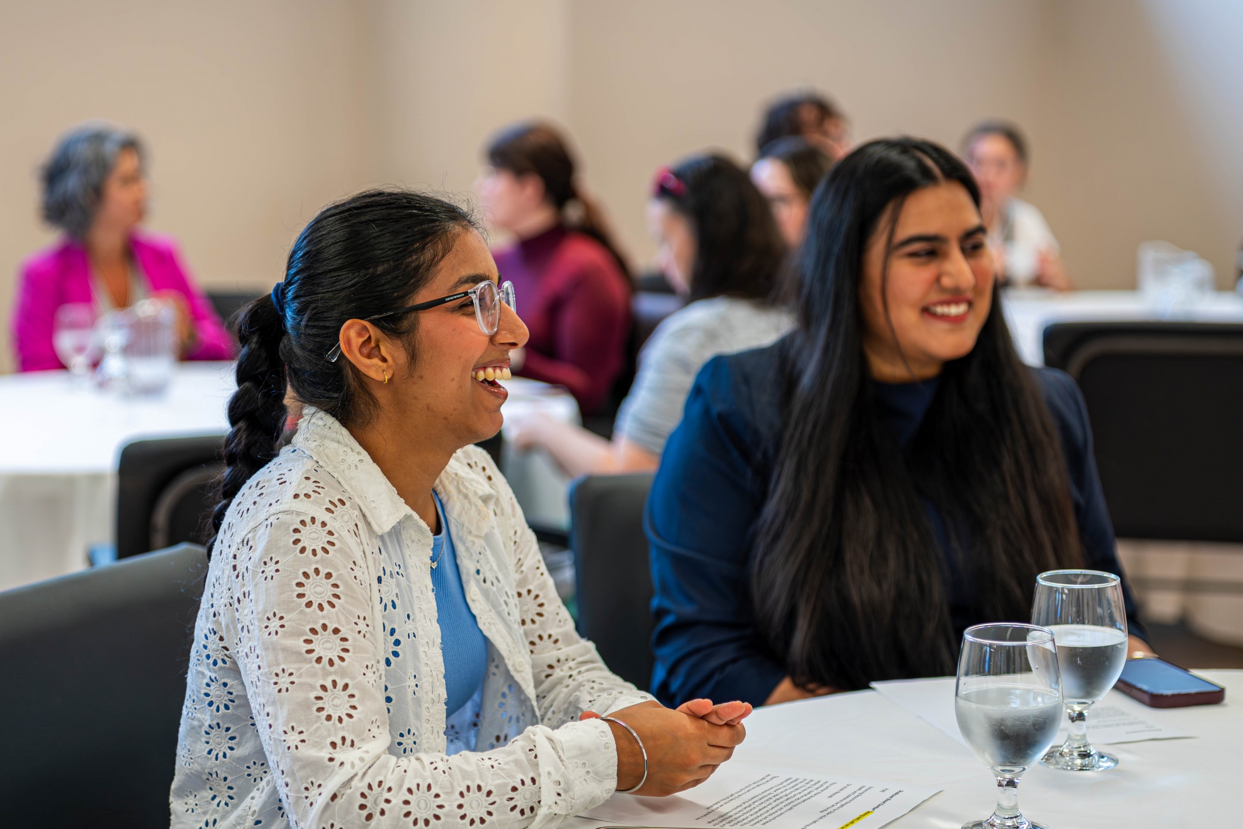 Two students laughing while sitting at a luncheon banquet table.