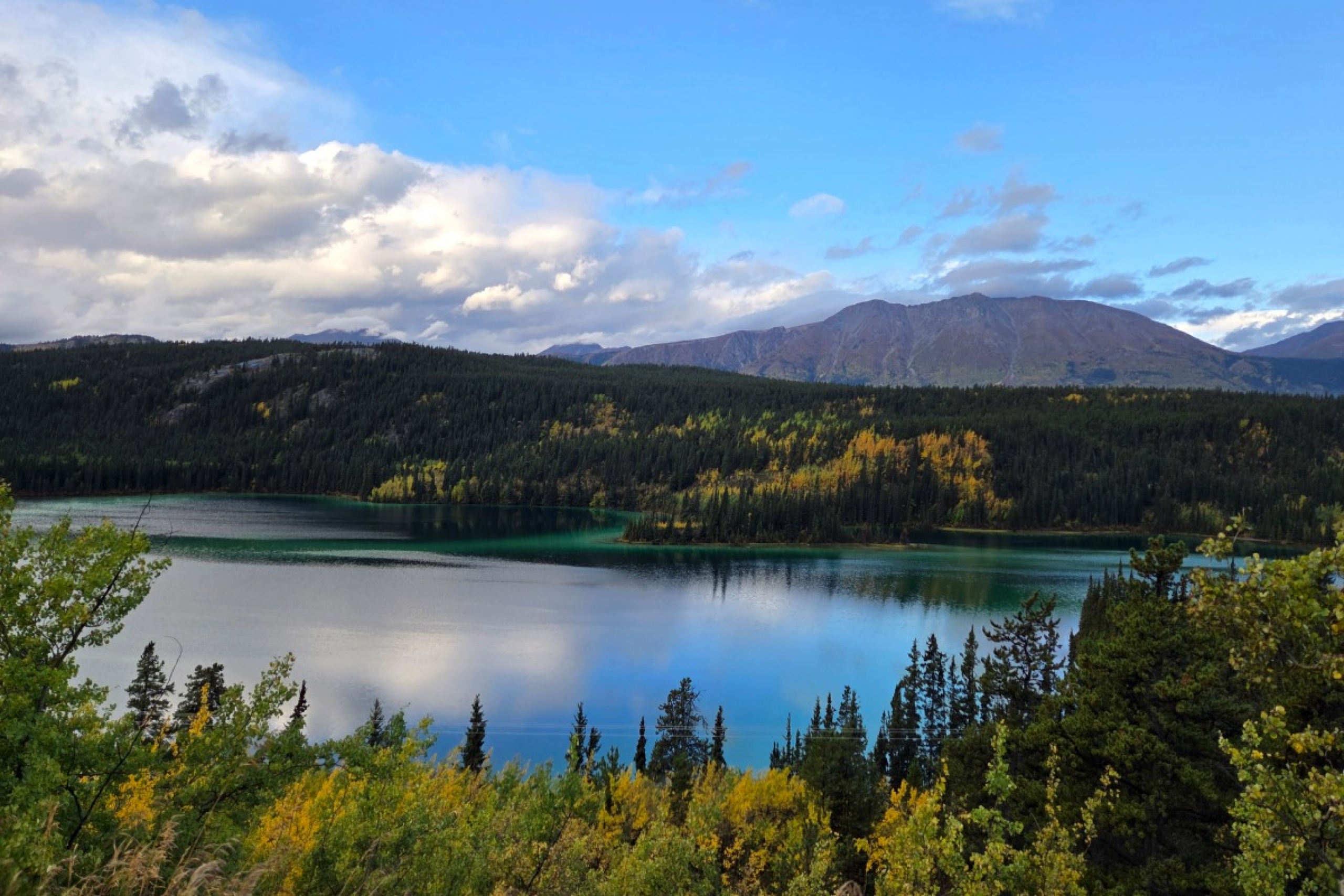 Landscape featuring mountains, a tranquil lake and clear blue skies.