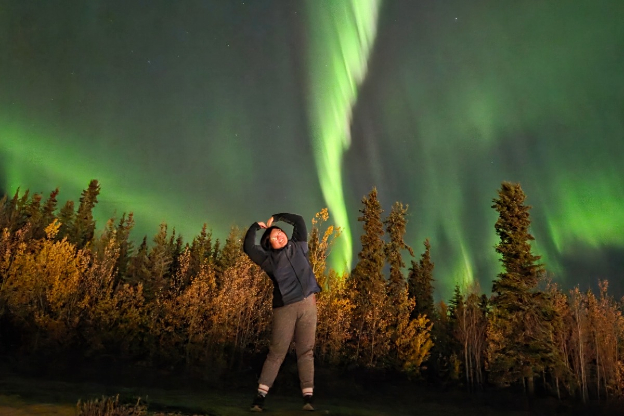 Sunjin Han smiling and posing under the Northern Lights.
