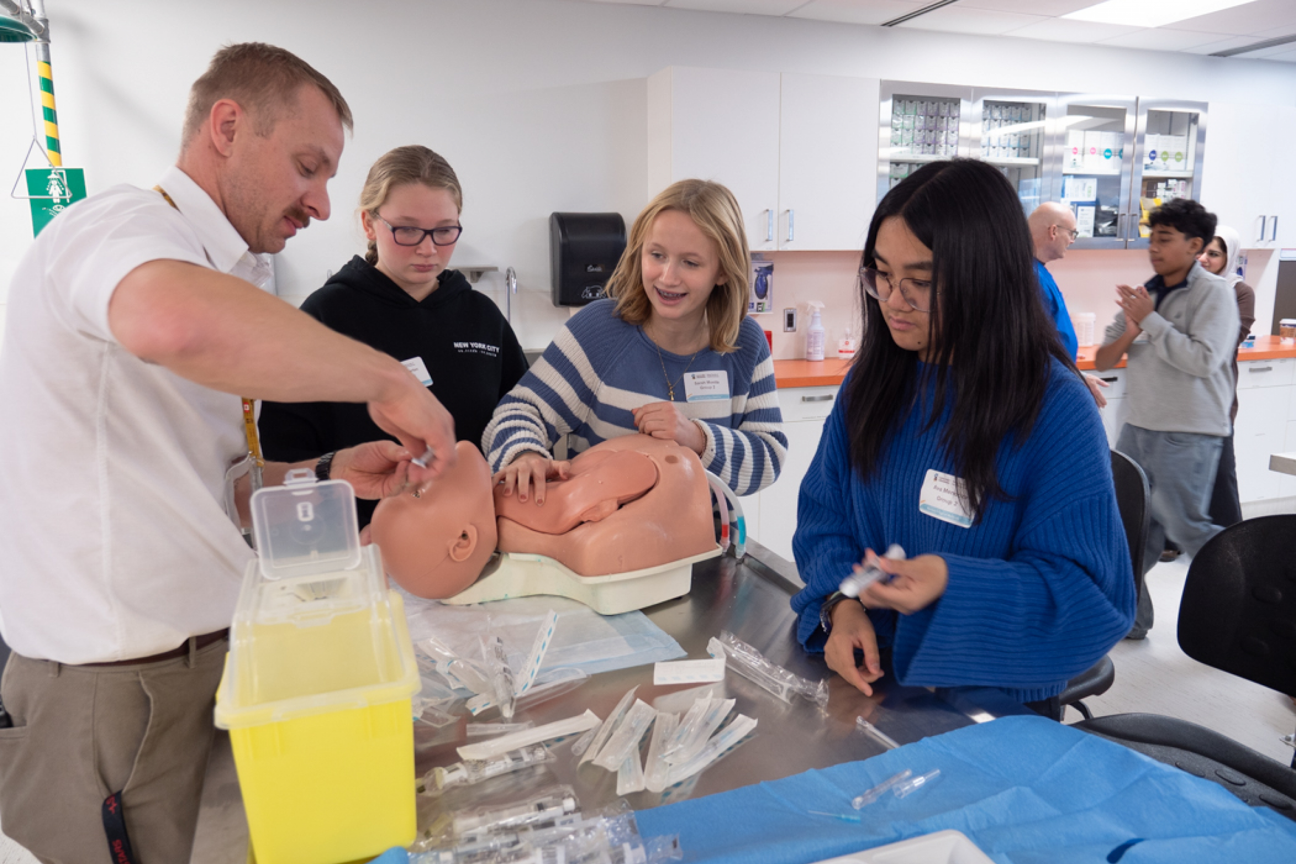 Danny Kustra, clinician educator at CLSP, supports students practicing on a manikin in a clinical skills activity.