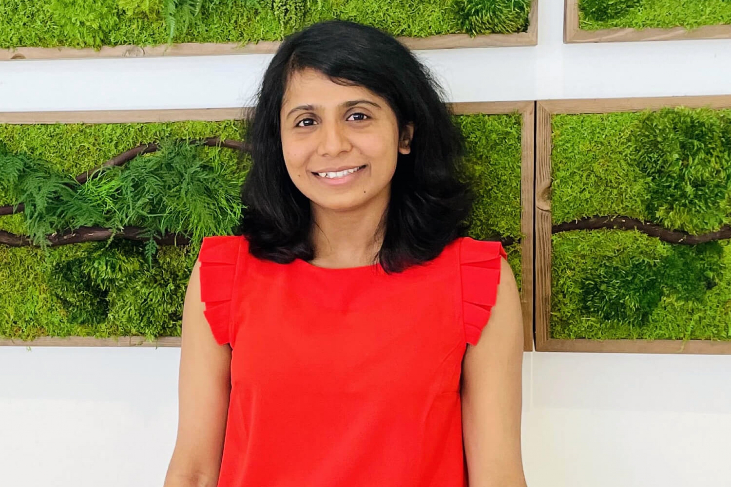 Dr. Thilini Dissanayake stands in front of a living wall.