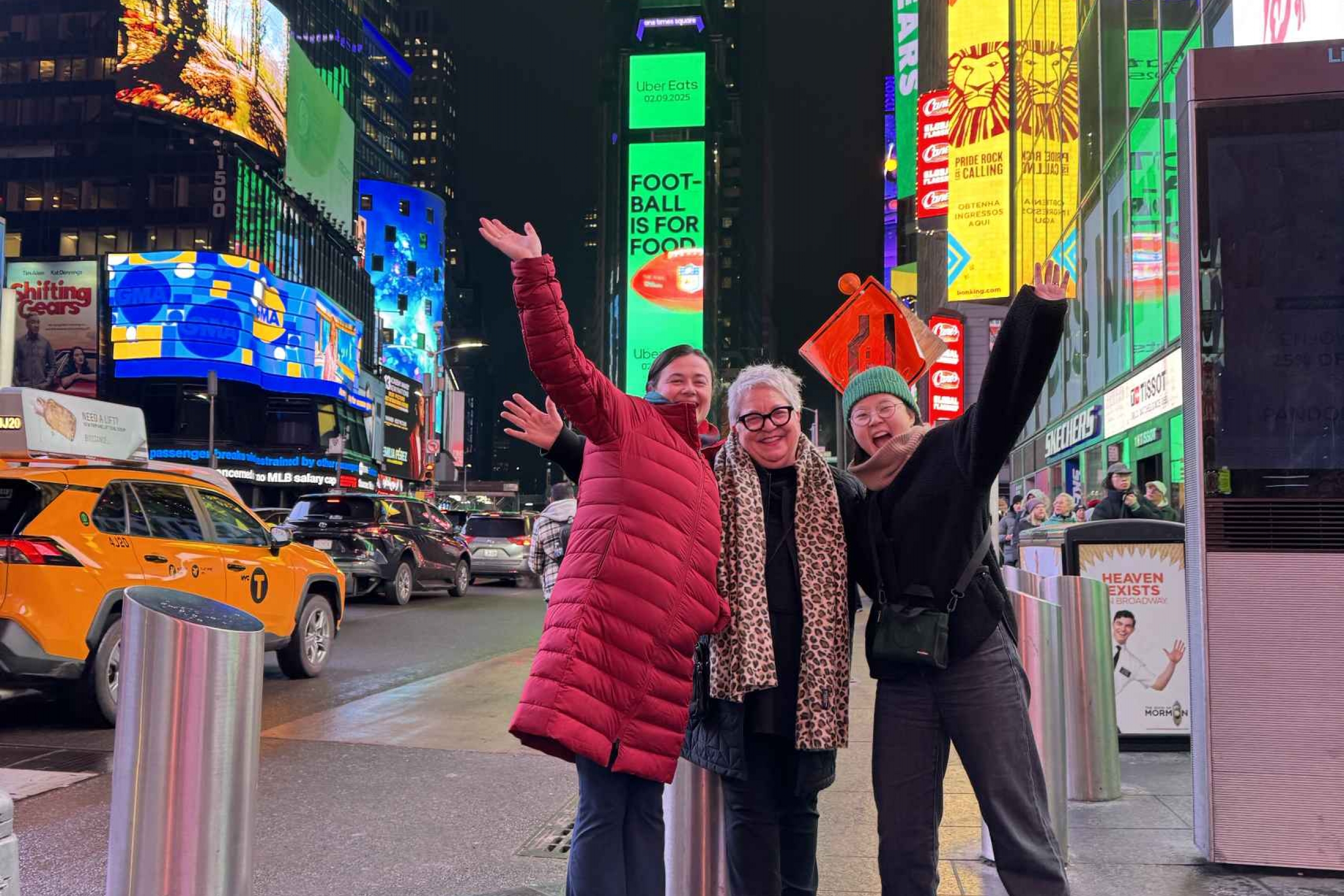 Three women pose together at Times Square.