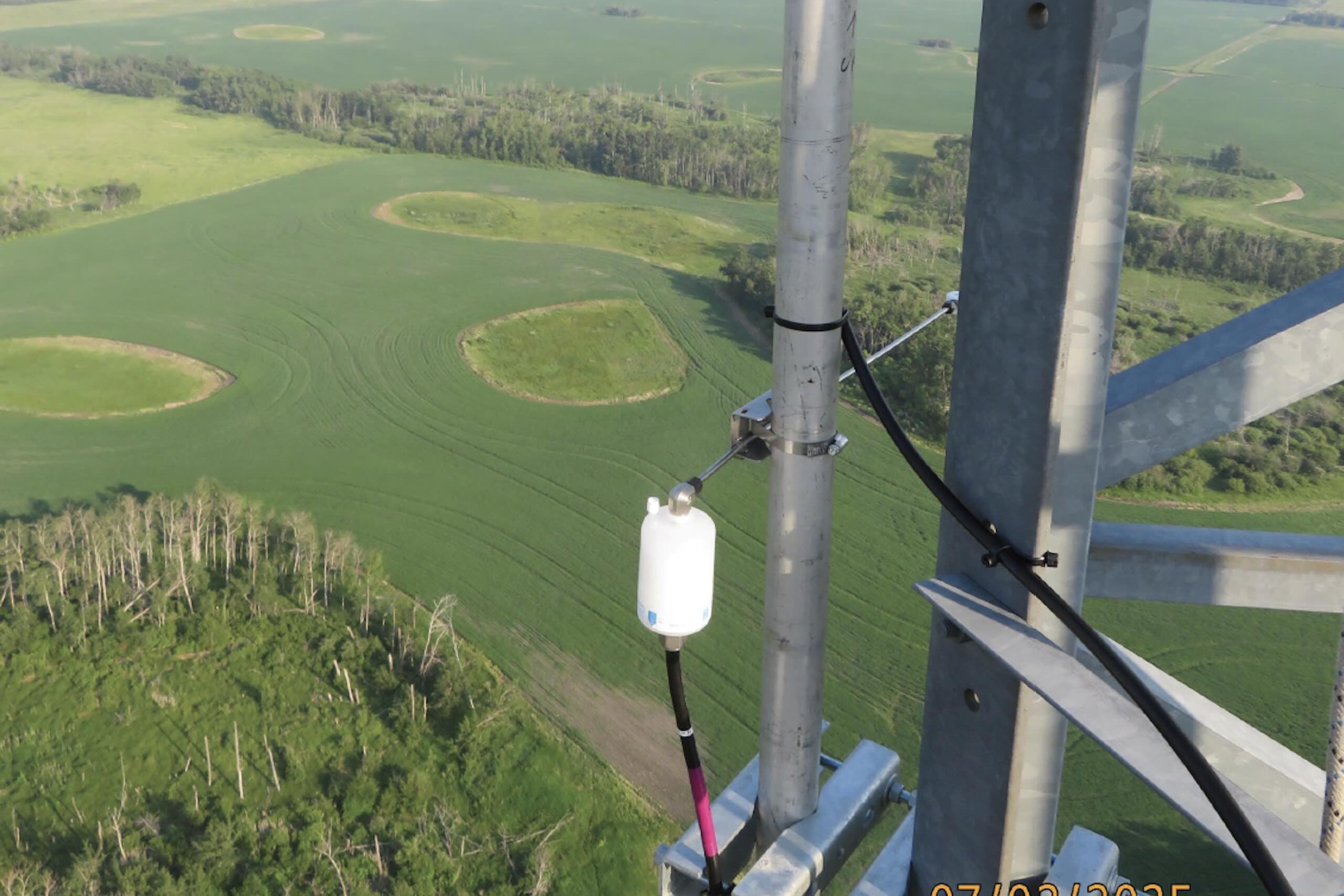 Aerial view to green fields below from tall tower.