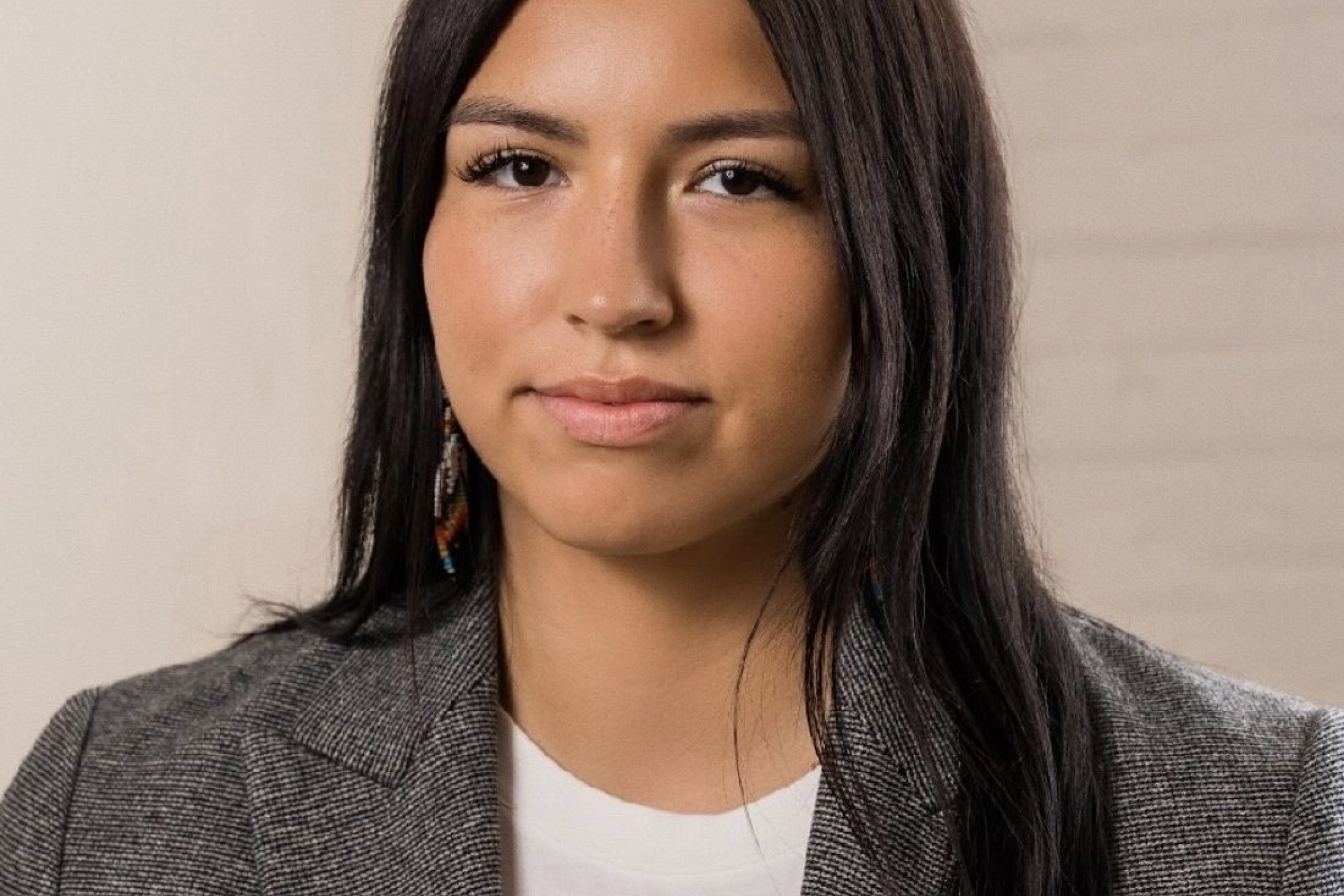 Trechelle Bunn, a young woman in a white t-shirt and grey suit jacket with long black hair and a calm, professional look of confidence.