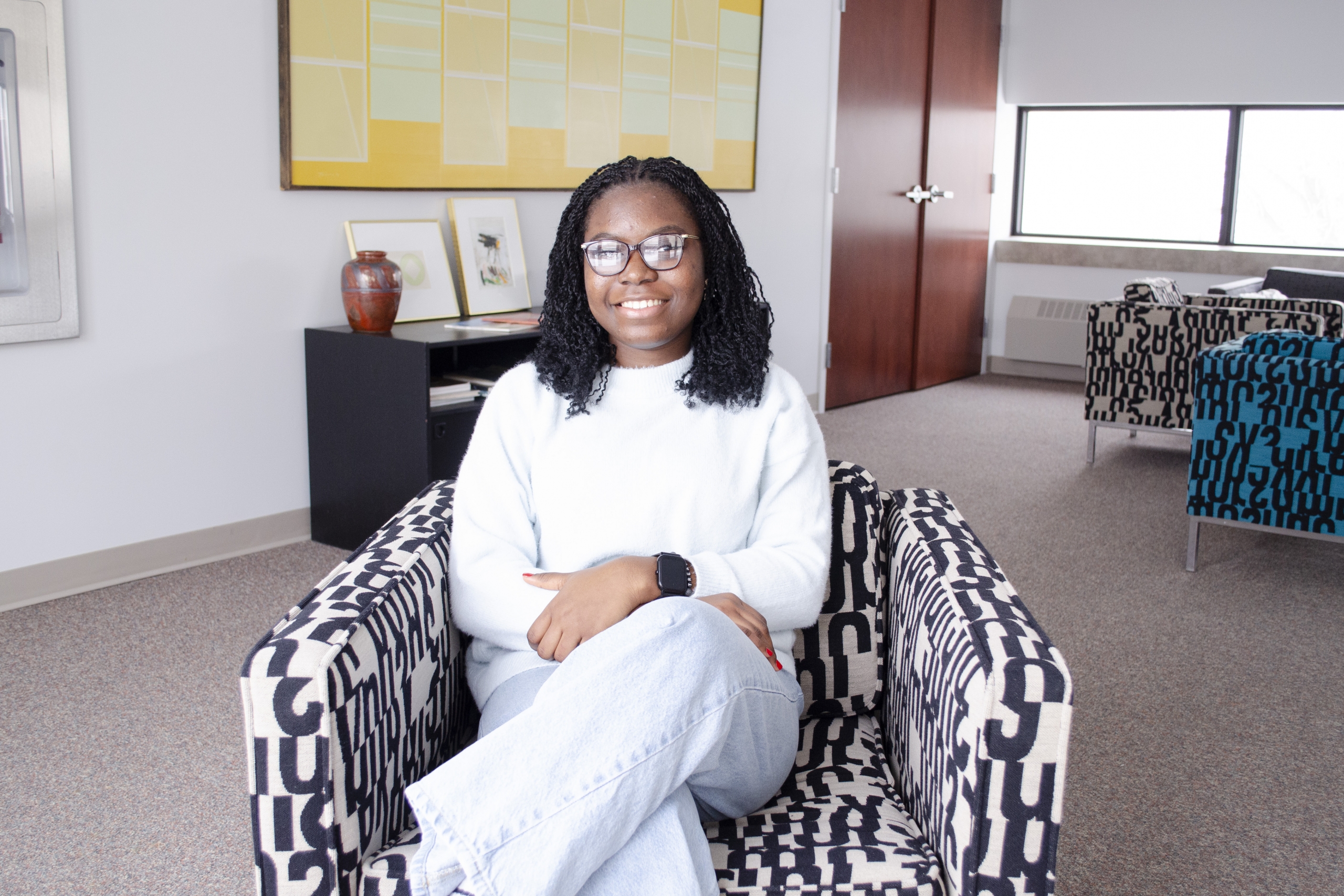 Treasure Johnson sitting on a chair with a colourful background