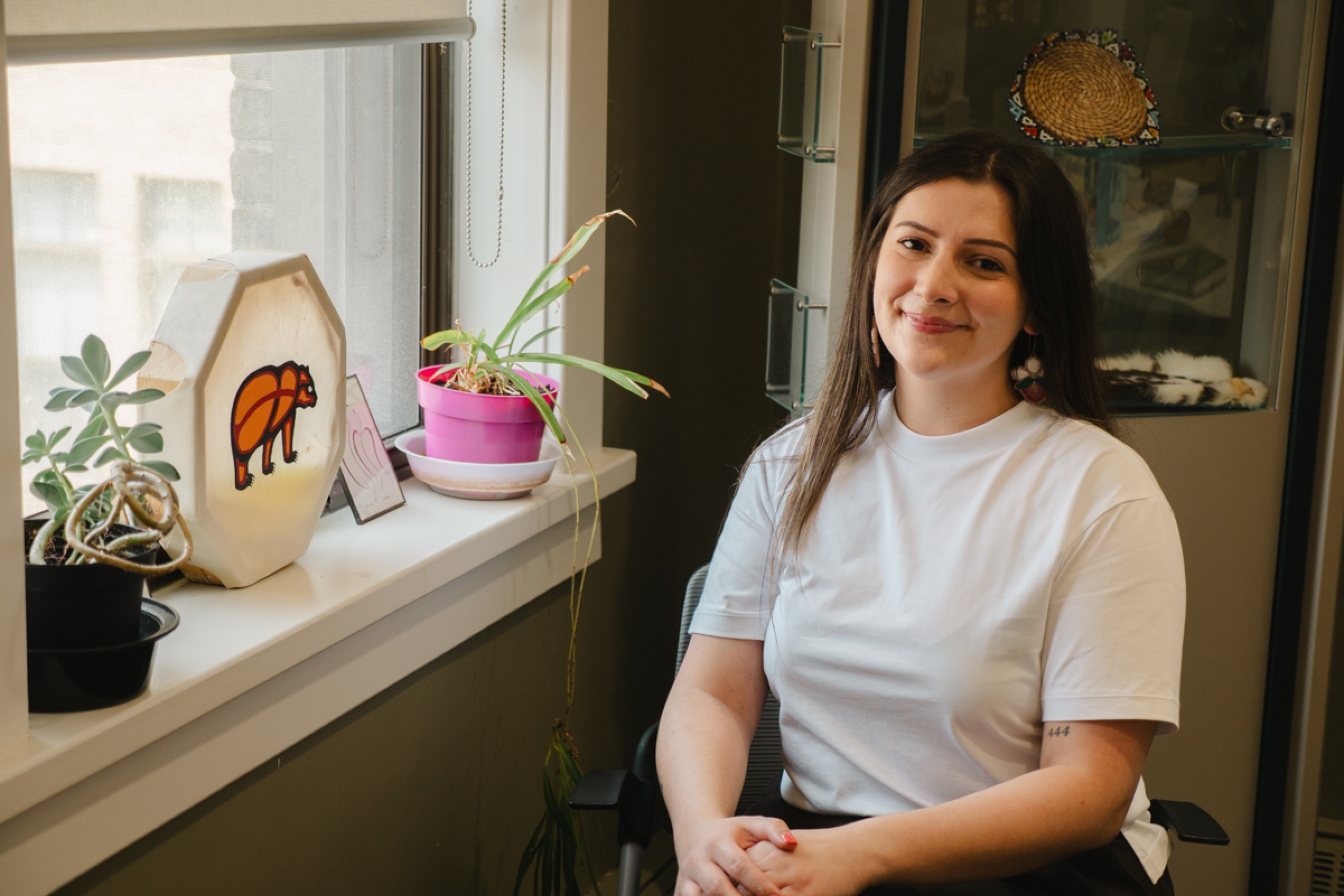 A person sitting and smiling at the camera by the window.