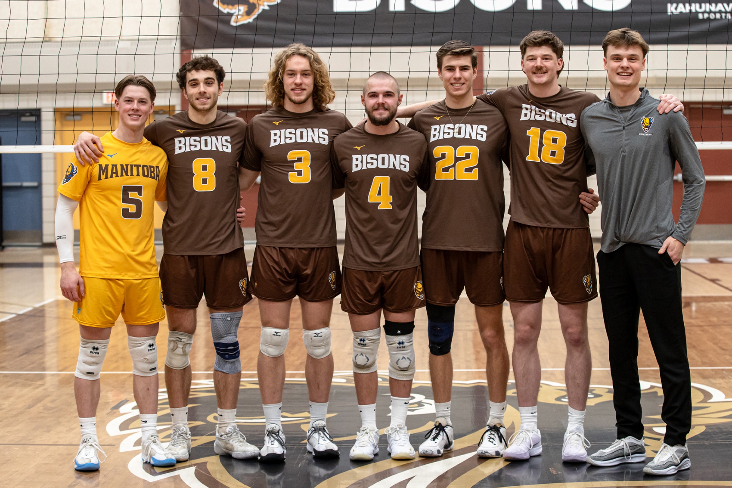 A group of men's volleyball seniors smiling together on the court