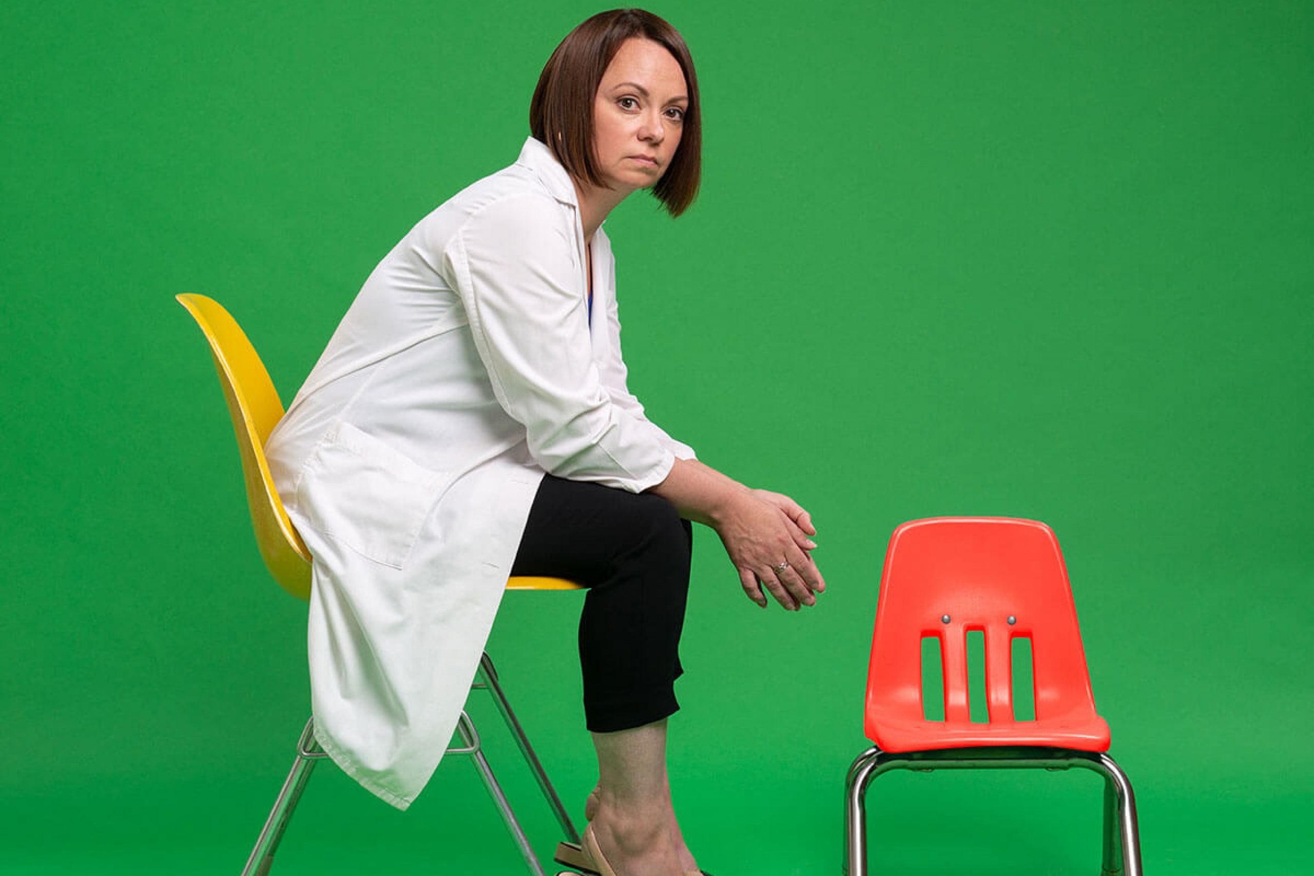 A woman sitting on a chair next to a smaller empty chair
