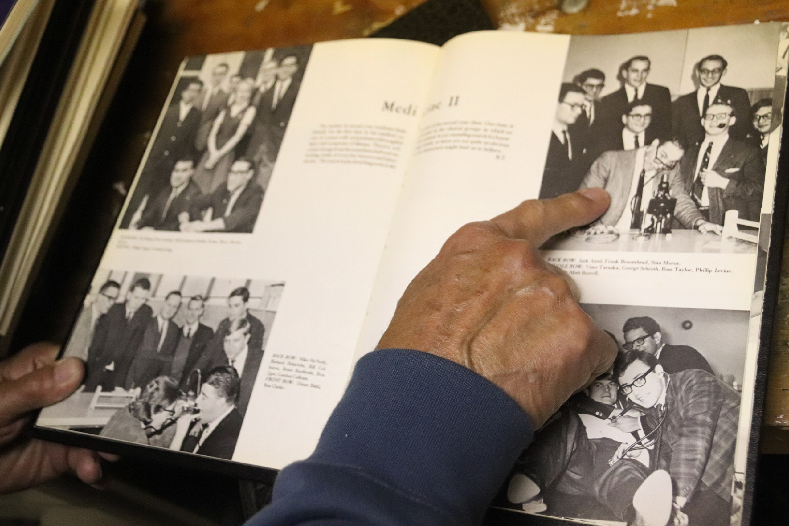 A hand points at an old photo in a yearbook.